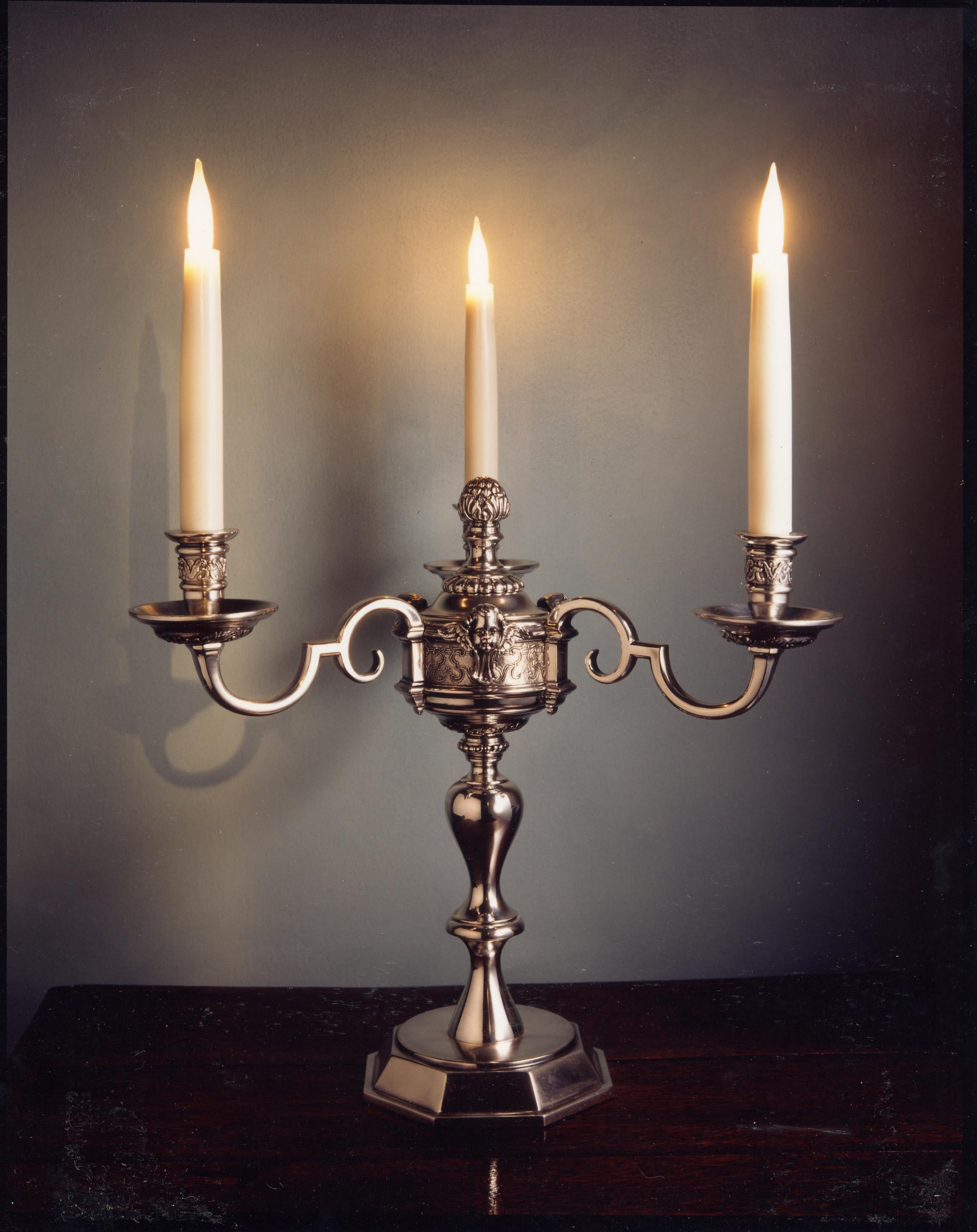 This was adapted from the silver chandelier hanging at Knole in Kent, exclusively for use in a conservation project at Hampton Court. It has an antique, silver plated finish. There is an old repair to a break in one of the arms on one candelabrum.