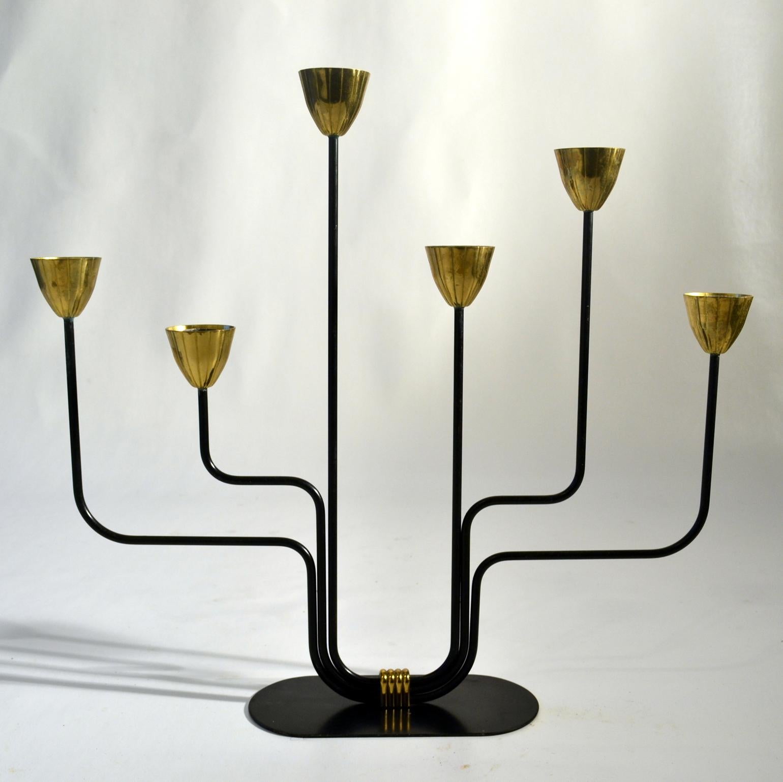 Gunnar Ander born, in 1976 Sweden, designed the candelabra for Ystad Metall, Sweden 1960's made of black lacquered metal arms and have six brass cup shaped candle holders for regular candles. Gunnar Ander inspired by the artistic developments of the