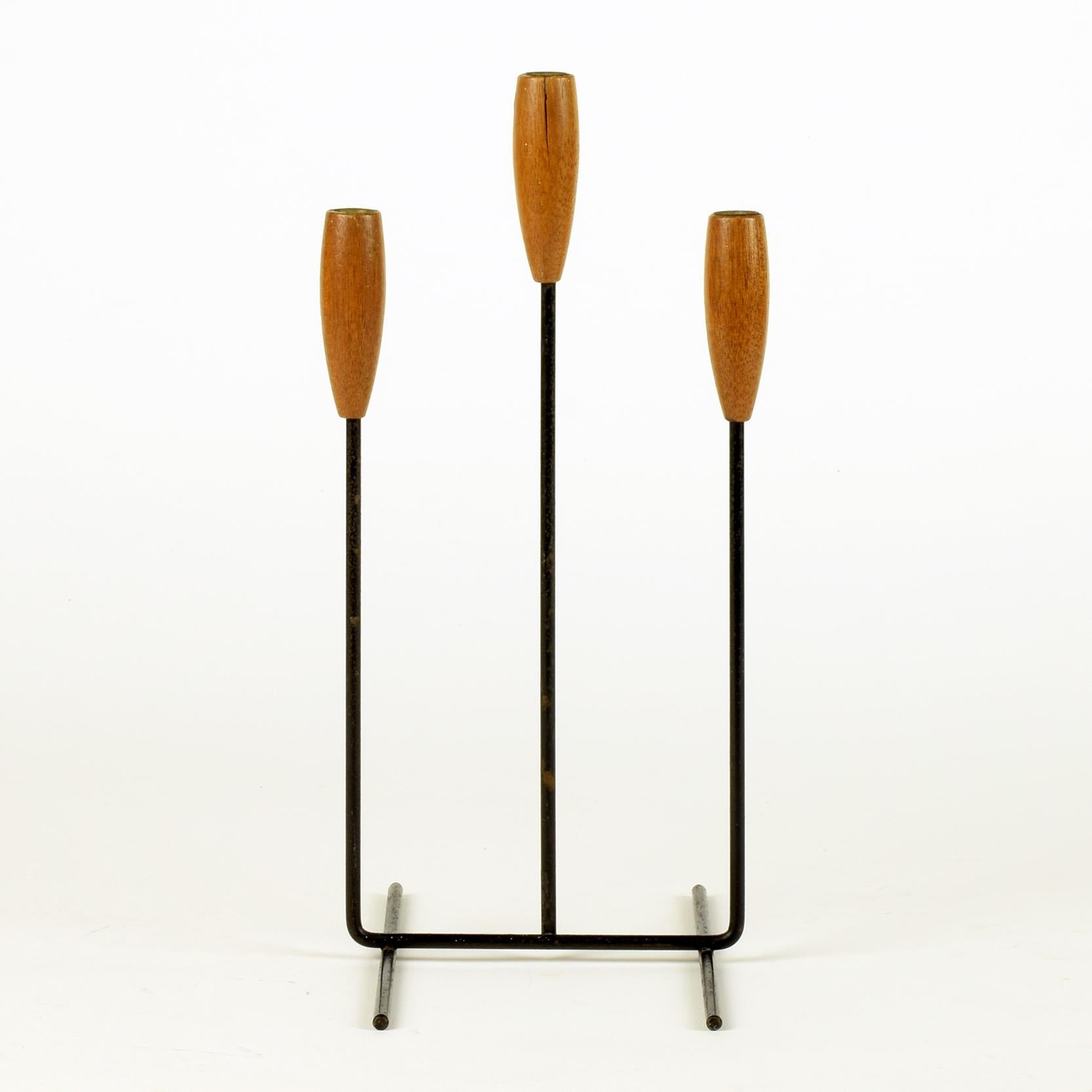 Candleholder for 3 candles, circa 1960

Teak, black metal.

A lovely midcentury item.
Overall very good with good age and patina. Slight split in wood to central holder, but this compliments the vintage feel of the piece.