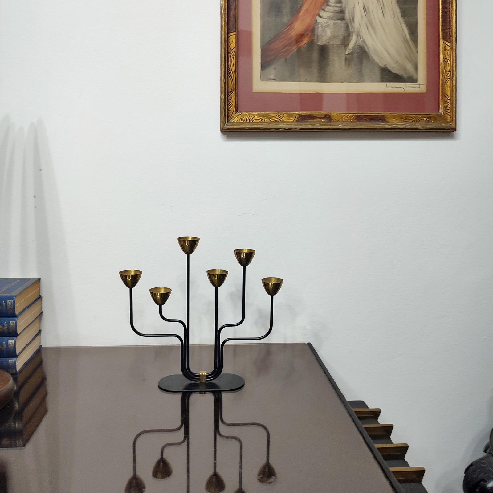 Candelabro modernista svedese di Gunnar Ander per Ystad-Metall. Ha dei portacandele in ottone (fiori stilizzati) su 6 bracci asimmetrici in acciaio smaltato nero.
Candelabro in ottone e metallo verniciato nero per candele sottili. Timbro 