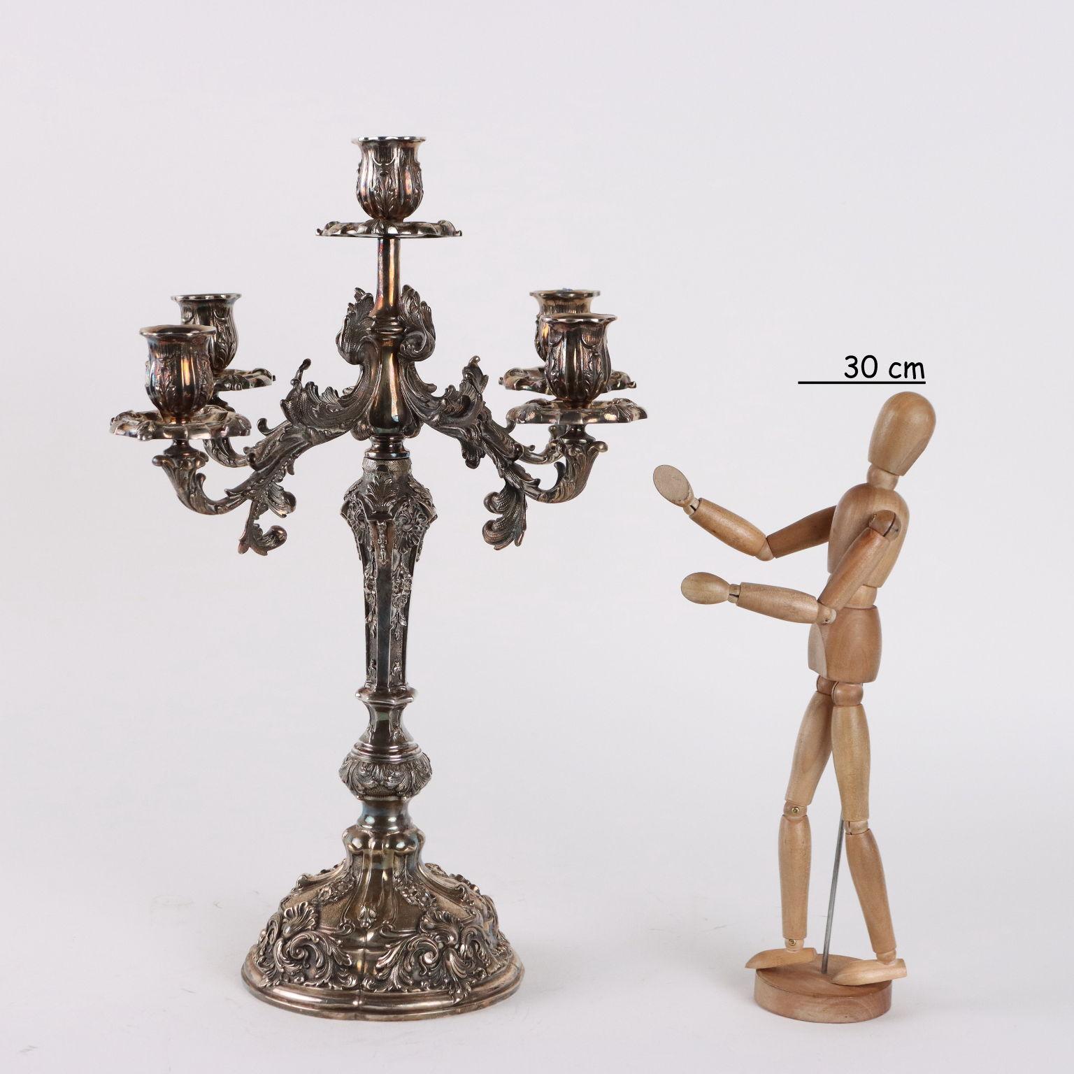 Five-flame silver candelabrum finely chiseled and worked by burin with plant motifs and leaf volutes decorations. Below the base silver and silversmith's marks. 3540 grams.
