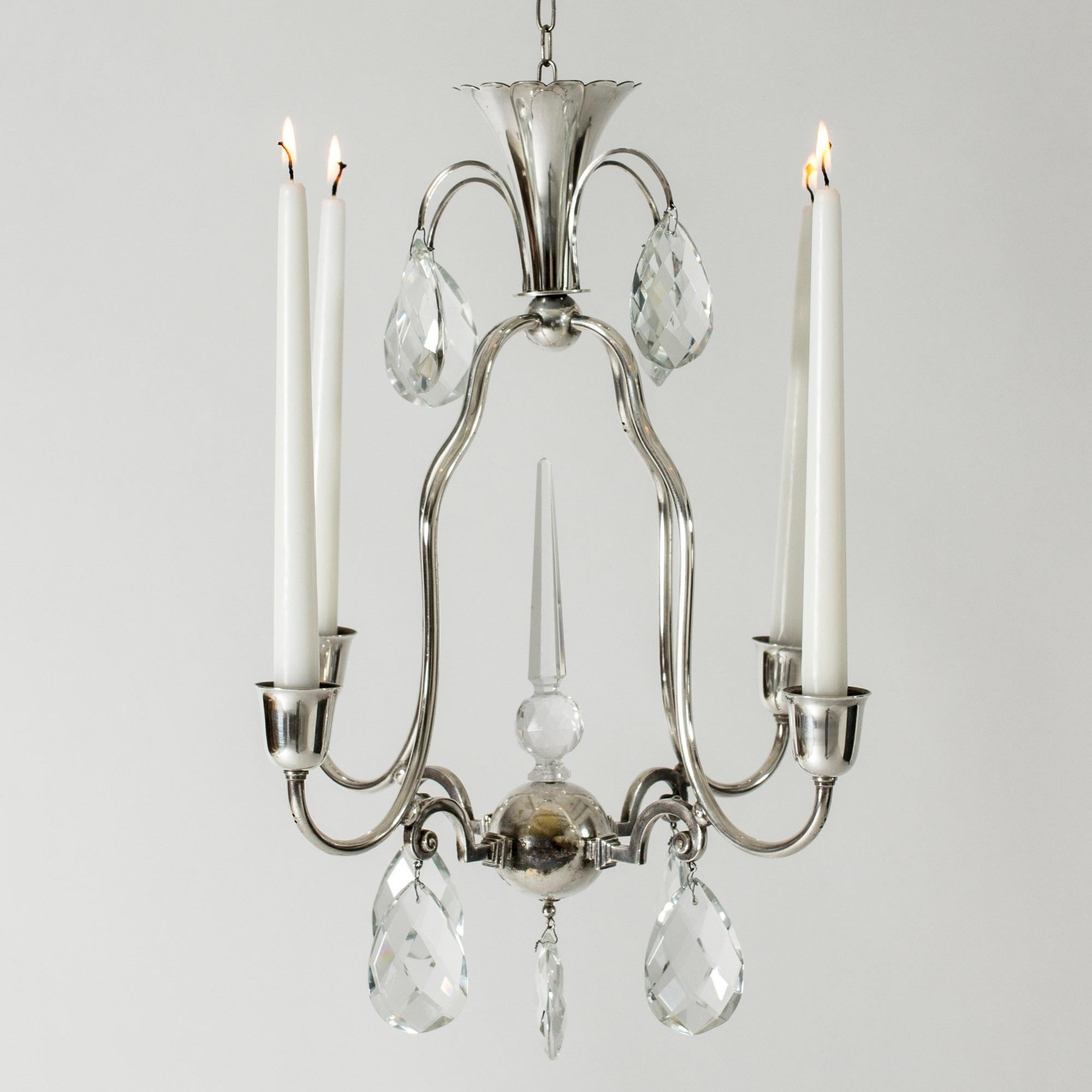 Beautiful Art Deco candle chandelier by Elis Bergh. Silver plated with large crystal prisms suspended at the top and at the base. Slim, decorative lines.