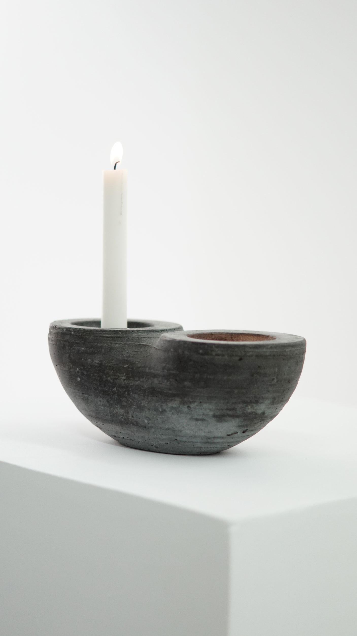 Candle holder for 2 candles.

At the intersection of art, craft, and design, Concrete Poetics' debut collection of hand-cast cement sculptural furniture and accessories streamlines visually intriguing and dynamic forms juxtaposing the density of the