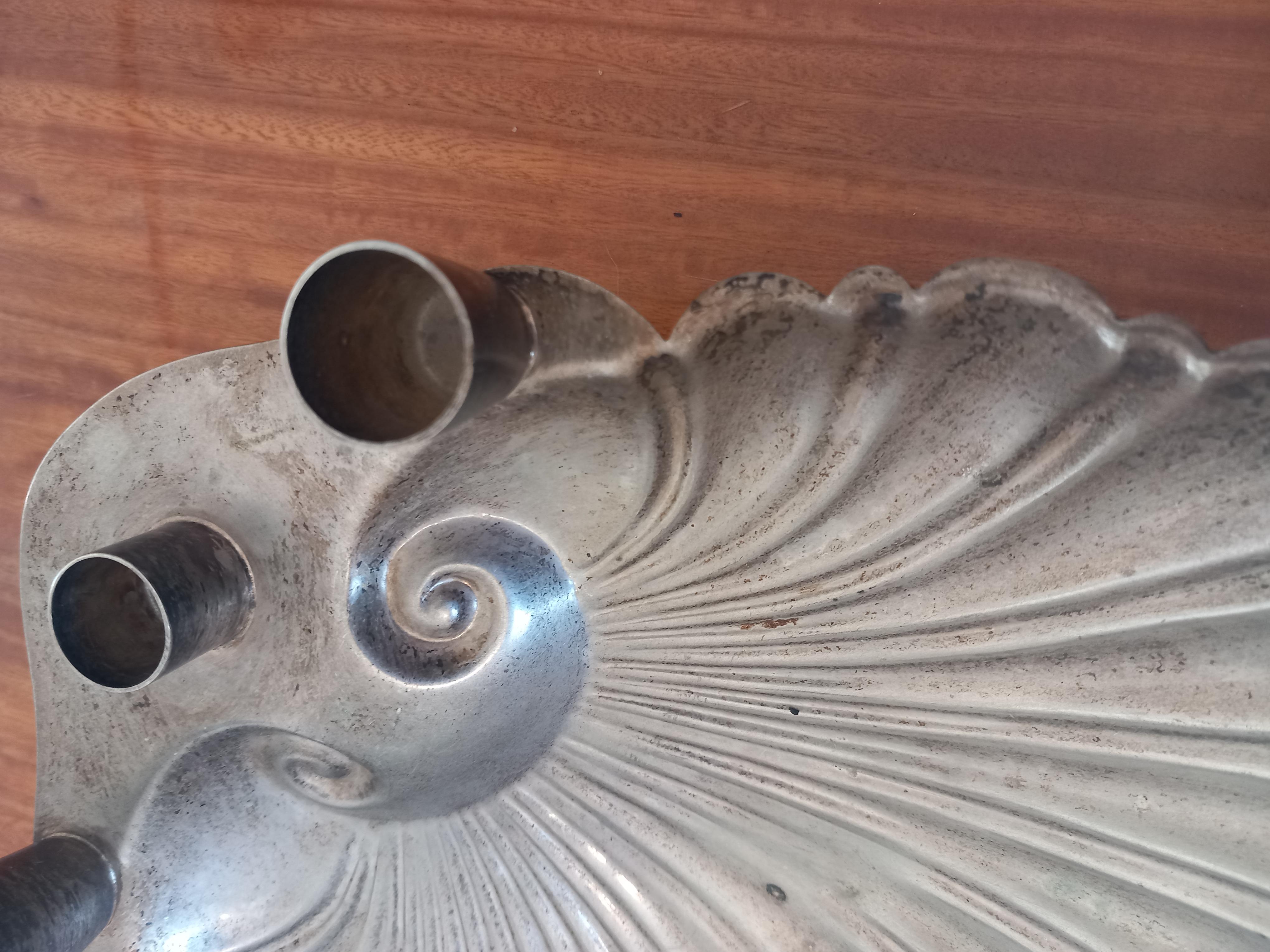 Candelabra or candle holder in the shape of a shell for 3 candles.

Metallic shell shape, silver, could be alpaca full-aged or nikel. I don't know what metal it is but it's very nice. It also has the patina of time, but it has no color wear.
