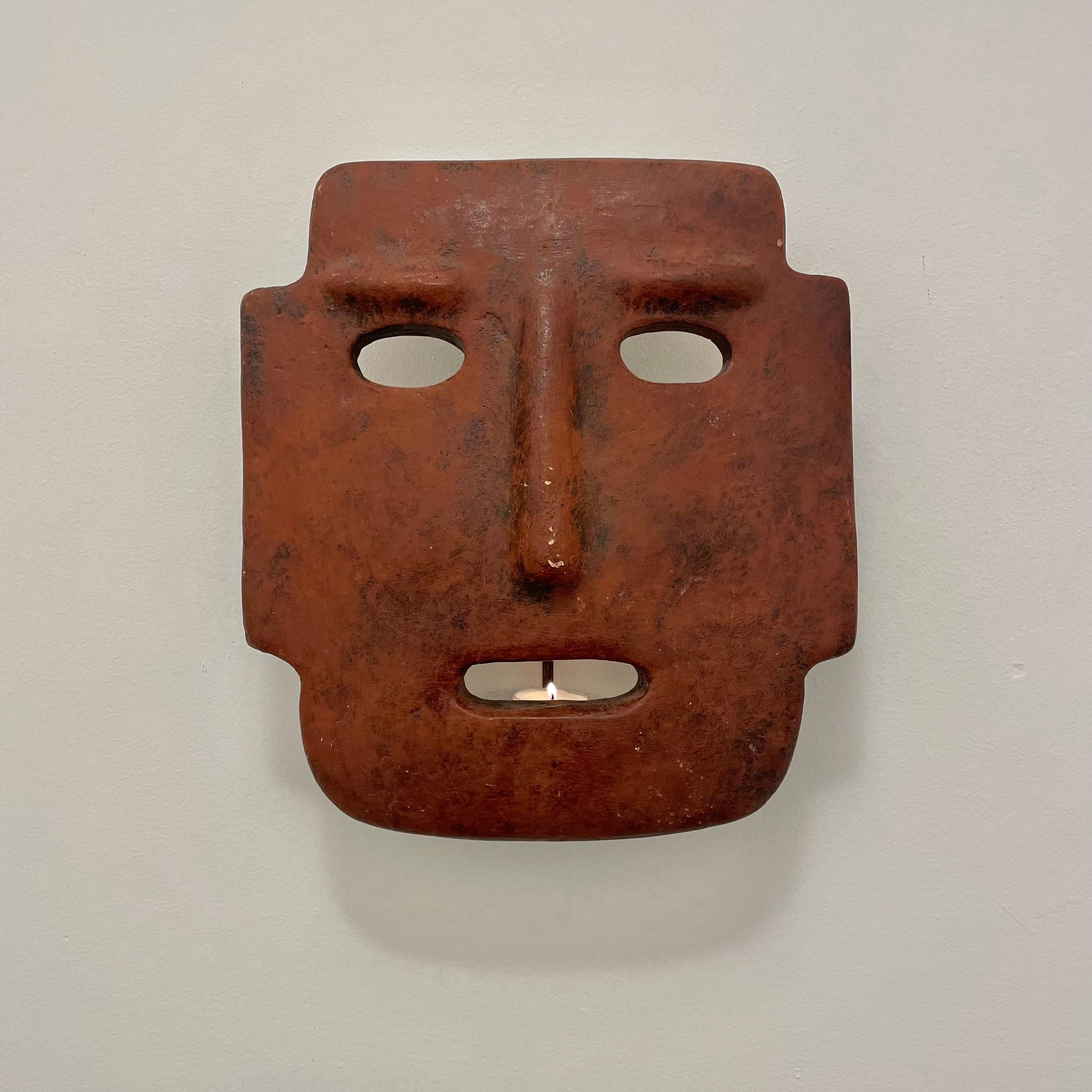 Fantastic sculptural clay mask candle sconce made in Italy. Hand made in an aged adobe color with a place for a single candle inside. Mask has a metal frame which gives the piece a nice depth from the wall and provides a surface for the candle to