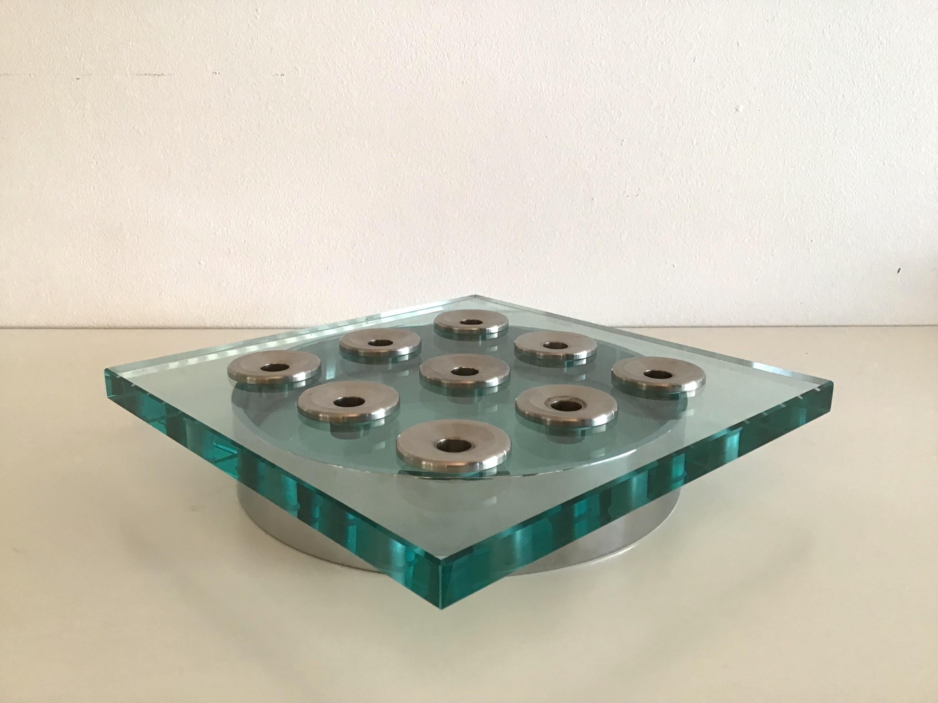Large centerpiece candle holder with 9 candles in glass and chrome metal. Consists of a thick, slightly beveled glass resting on a chrome metal circle and a glass disc.
