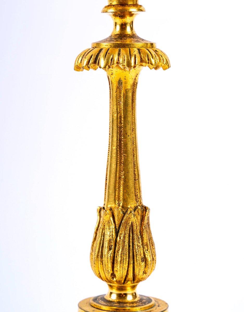 Lovely candlestick in chiseled bronze and gilded with mercury. Its fluted base rests on three top feet, a very pretty knot decorated with interlacing comes to sublimate a fluted shaft decorated with palmettes surmounted by a sleeve with a garland of