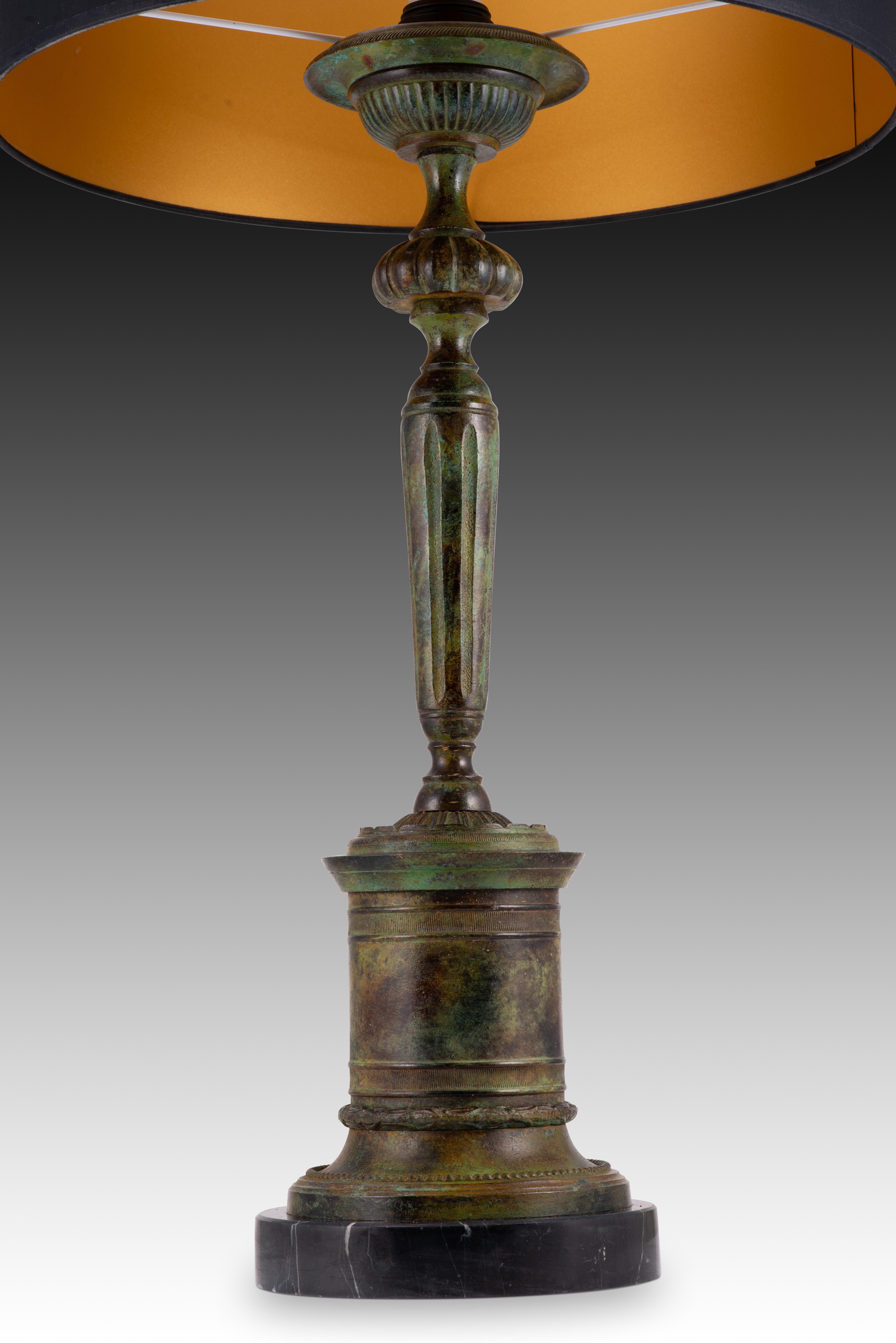 Kerzenständer-Lampe, patinierte Bronze. Sockel aus schwarzem Marmor. 
Ohne Schatten. 
Ein runder Sockel betont den Fuß der Leuchte: Der runde Sockel dient als Podest für einen kerzenförmigen Aufsatz und wird von einem Sockel für die Glühbirne