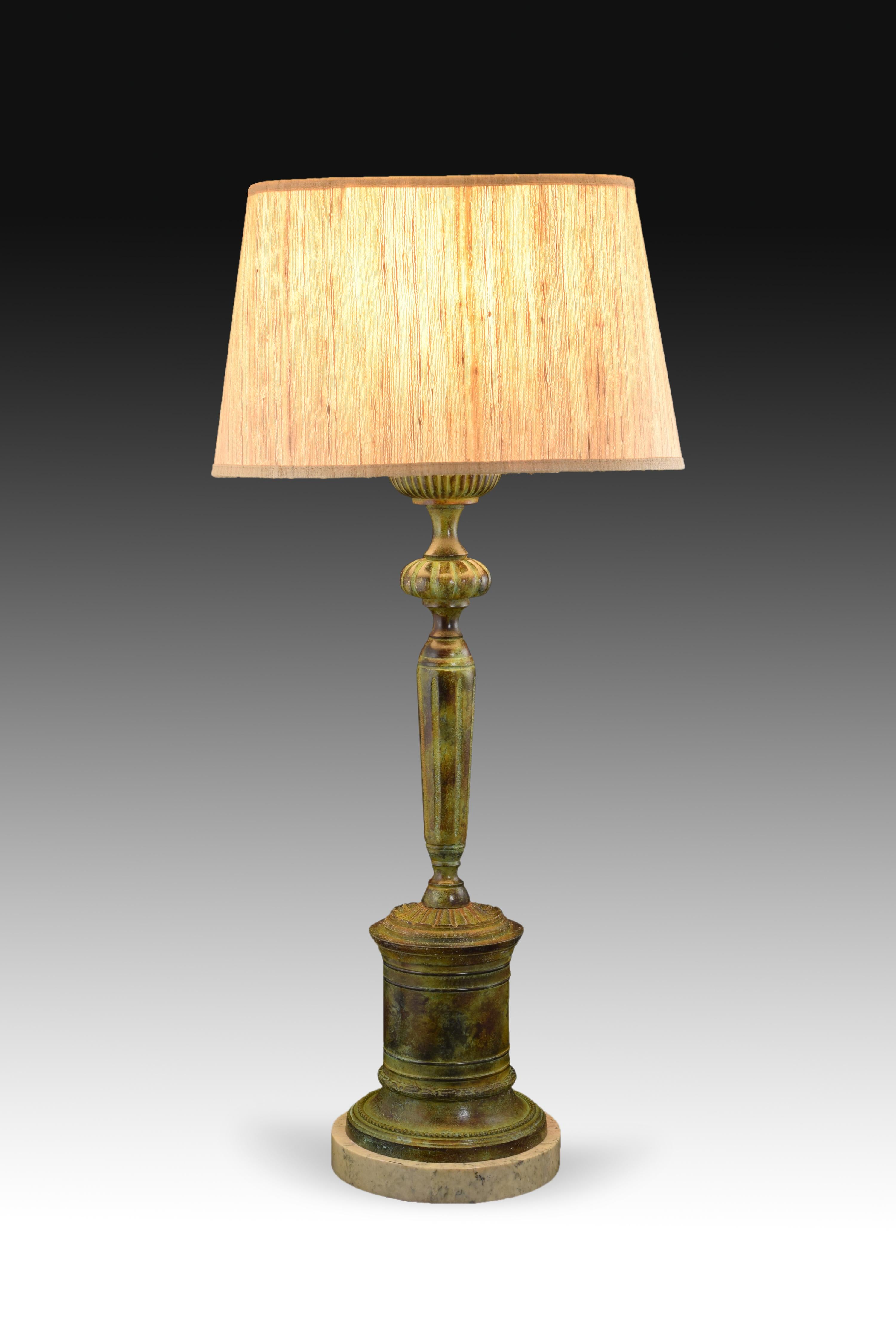 Chandelier shaped lamp, patinated bronze. Marble base. Without screen.
A round base enhances the foot of the lamp: the circular base serves as a podium for a candle-shaped piece and finished off by the base for the bulb; the difference in profiles