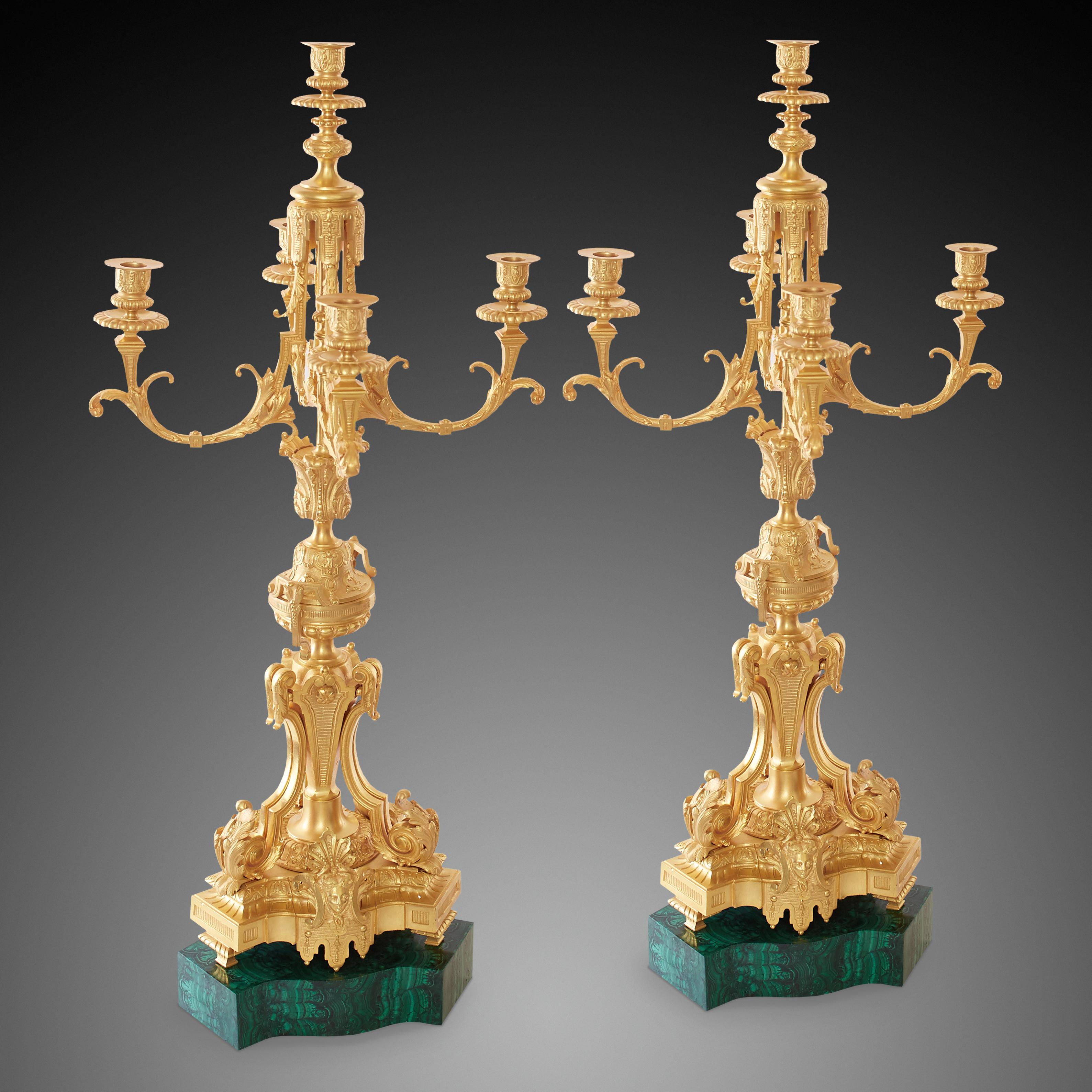 Each candlestick is placed on a stone made of malachite on which there is a base decorated with floral forms with the image of a woman's face on both sides. Above there are four decorative arms and a central frame located in the center.Everything