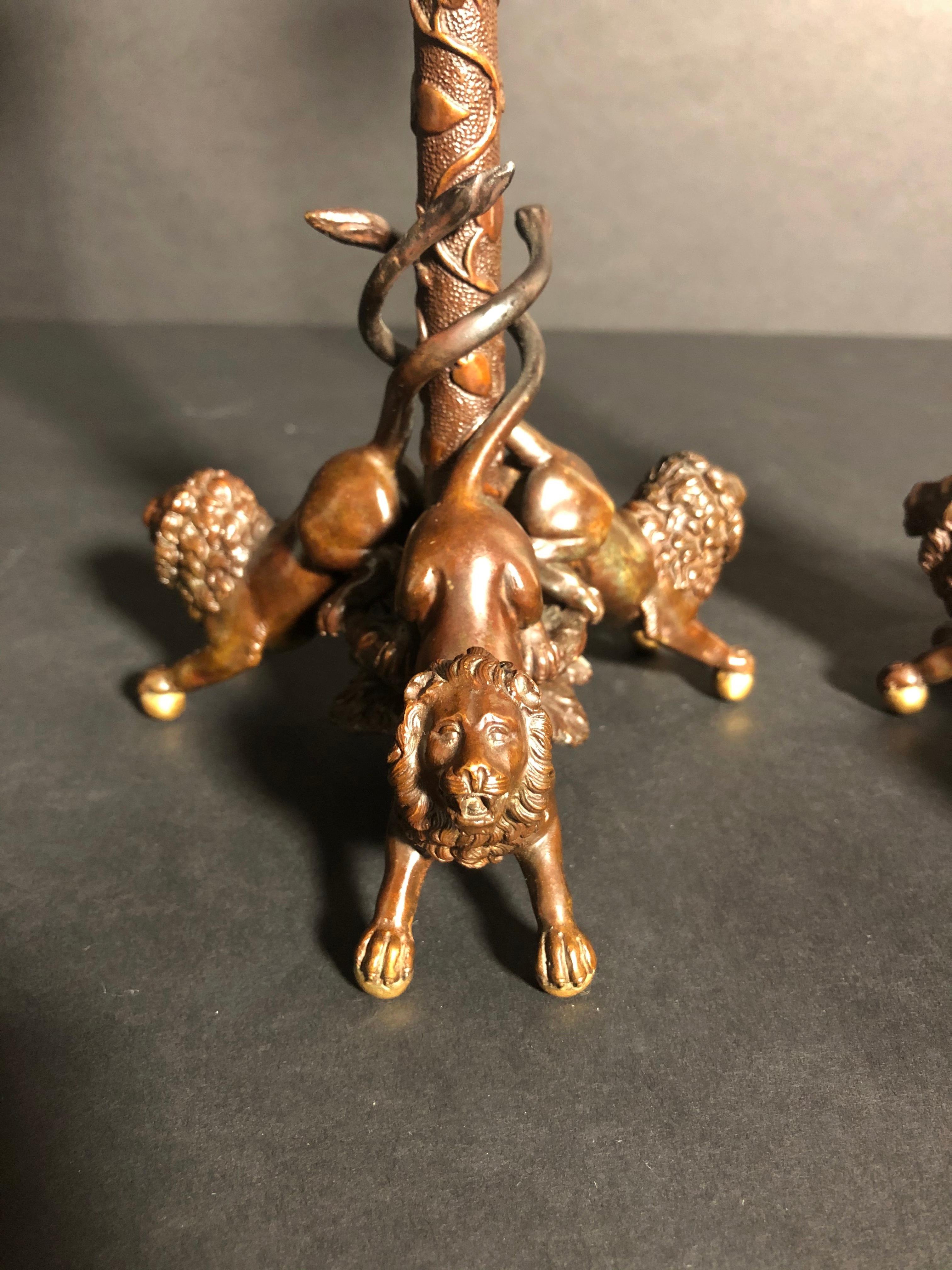 Hochwertiger, paketvergoldeter und patinierter, figuraler Kerzenleuchter des 19. Jahrhunderts mit drei Löwen auf Kugelfüßen, die eine mit Blättern und Ranken bedeckte Säule umschlingen, die einen Kerzenbecher mit Widderköpfen, Trauben und Blättern