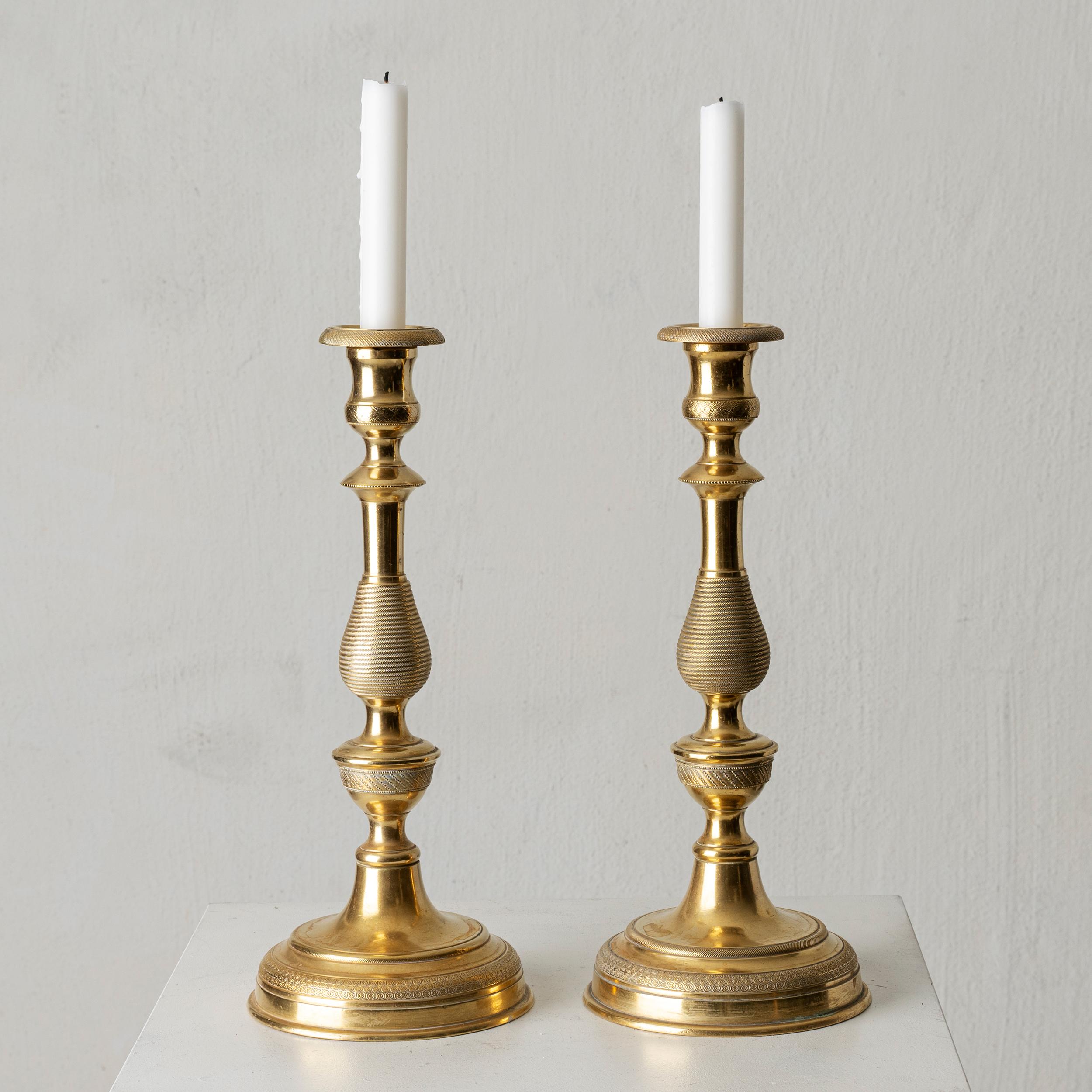 Una coppia di candelieri realizzati in Francia durante il tardo periodo dell'Impero. Realizzato in bronzo dorato. Poggia su un piede rotondo con un gambo a forma di balaustro. Polsini allentati.