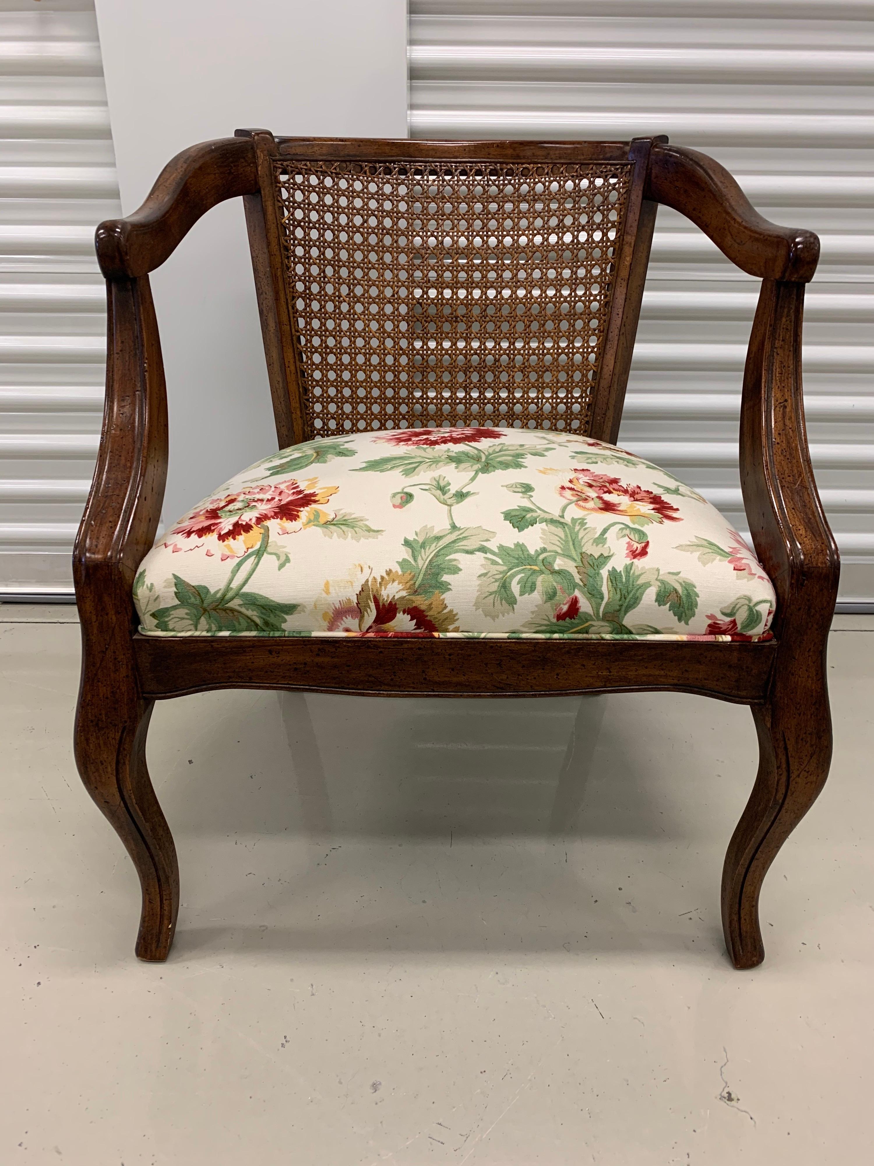 Elegant open air cane back armchair with a lovely, newer upholstery showing a floral pattern.