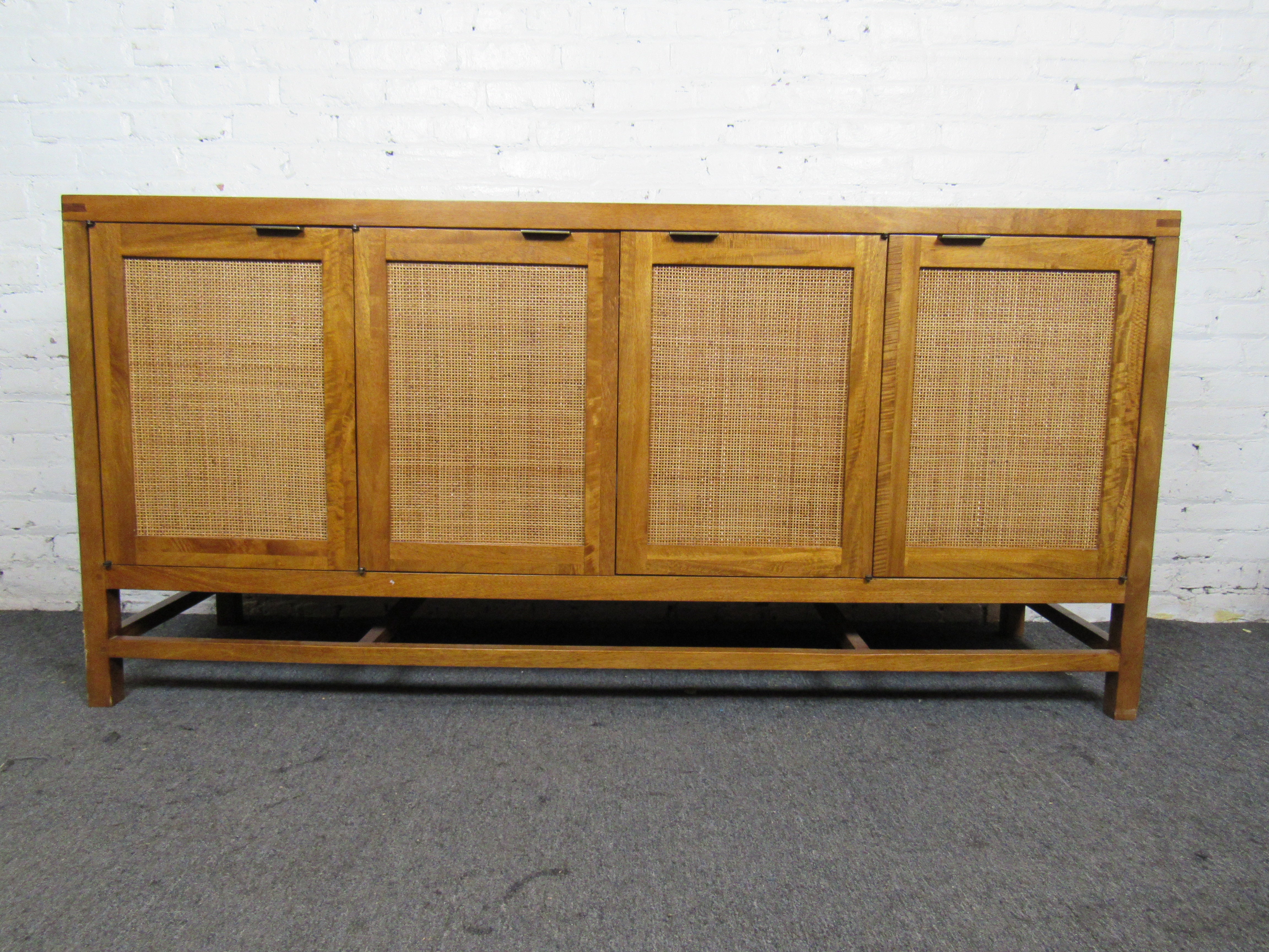 This vintage long cabinet combines woven front panels with an elegant Mid-Century Modern design. Four doors open to reveal large storage compartments for organization and functionality. Please confirm item location with seller (NY/NJ).