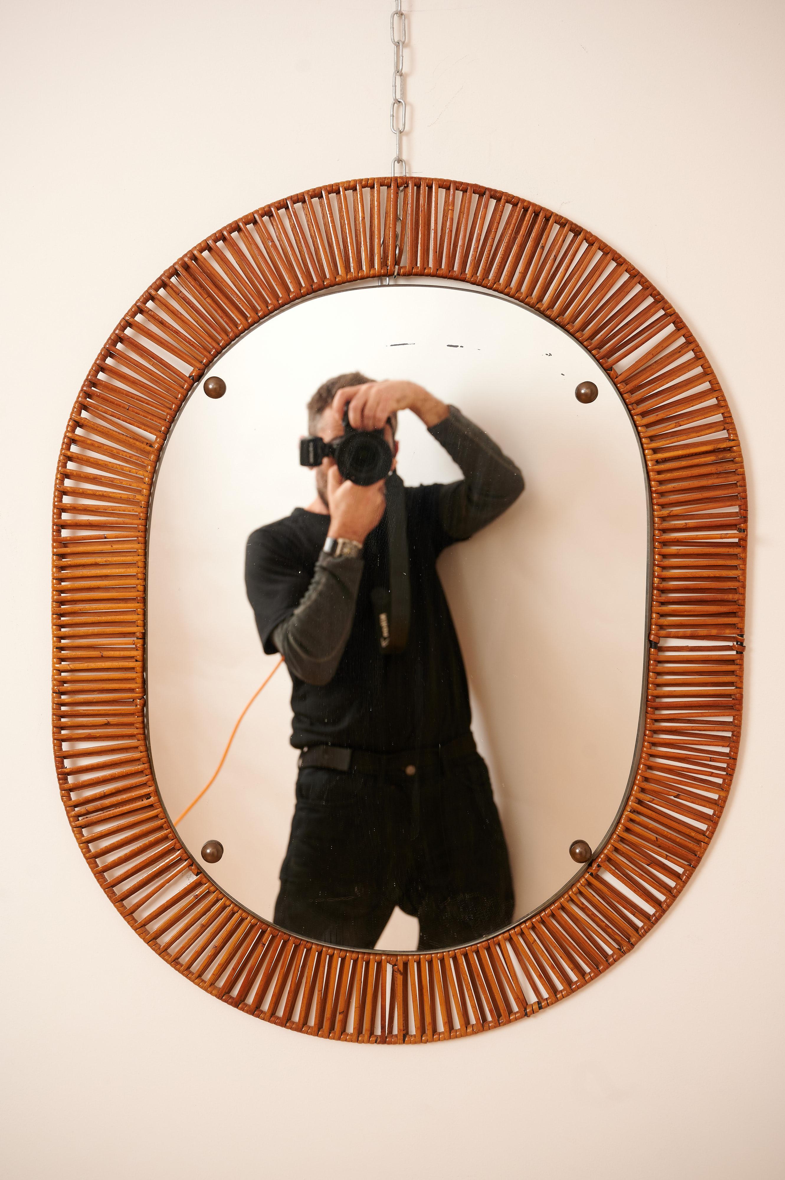 A wall mirror, produced in Italy c1950. 
Cut mirror glass is framed with rattan. With brass details.

Nice light patina to mirror.

Designers at this time were Gio Ponti, Max Ingrand, Charlotte Perriand, Joseph Frank and Franco Albini. Bonacina