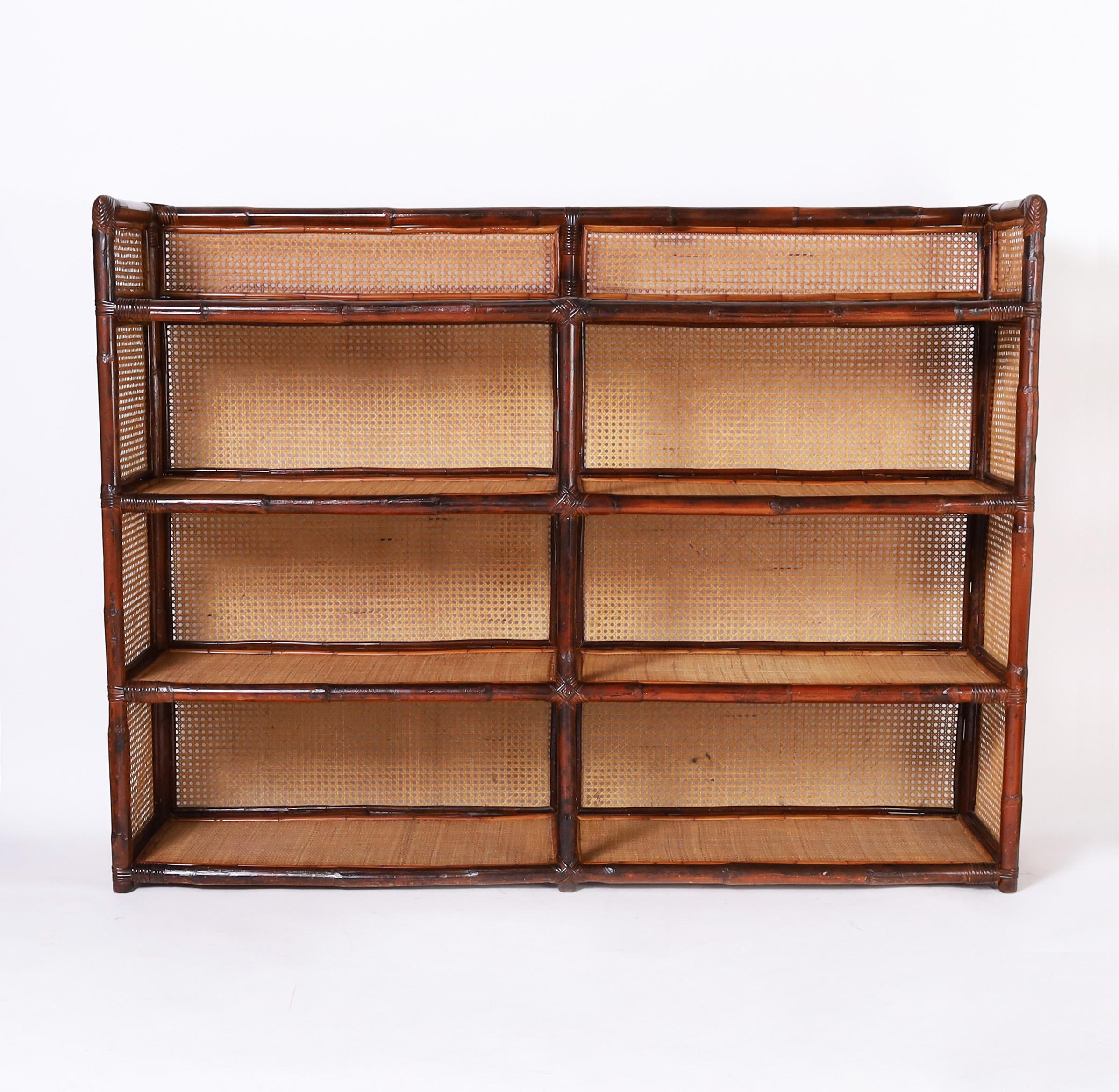 Impressive mid century etagere crafted with a bamboo frame supporting four grasscloth covered shelves with caned backs and sides.
