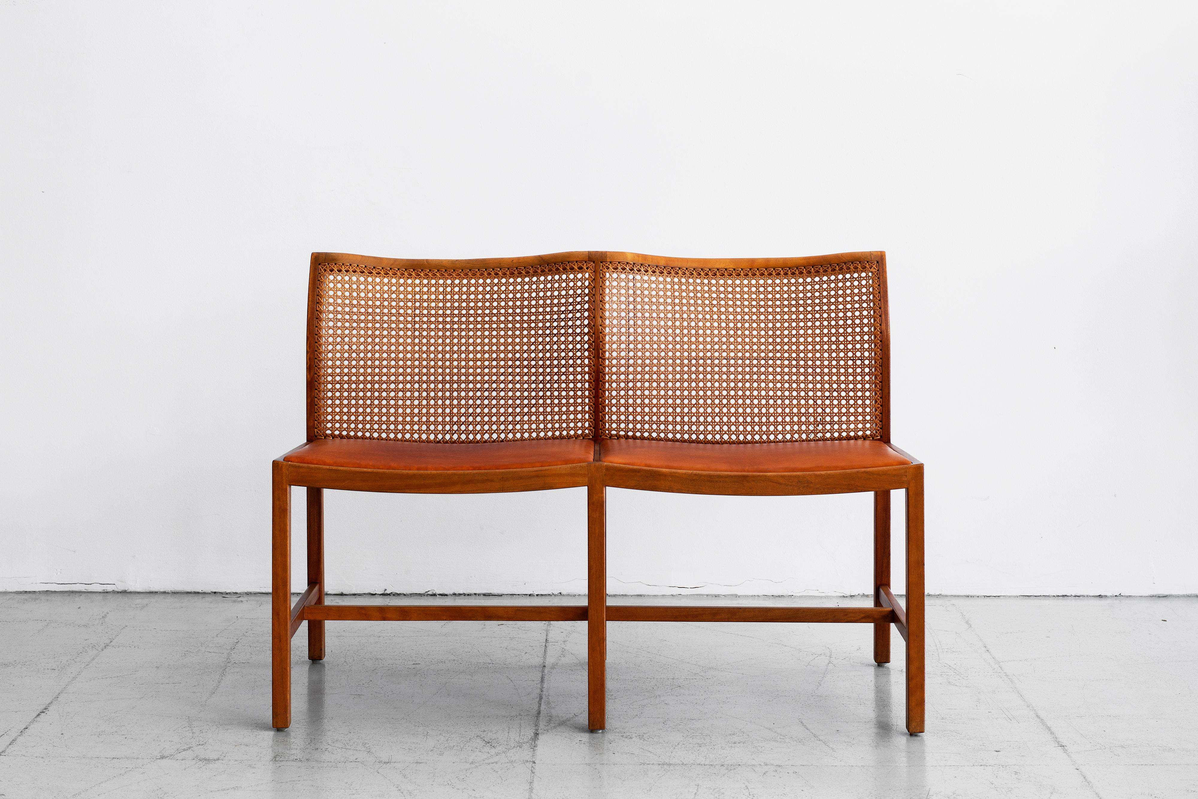 Minimalist Danish caned bench by Ditte & Adrian Heath. Leather seat and curved caned seat backs. Unique undulating shape.