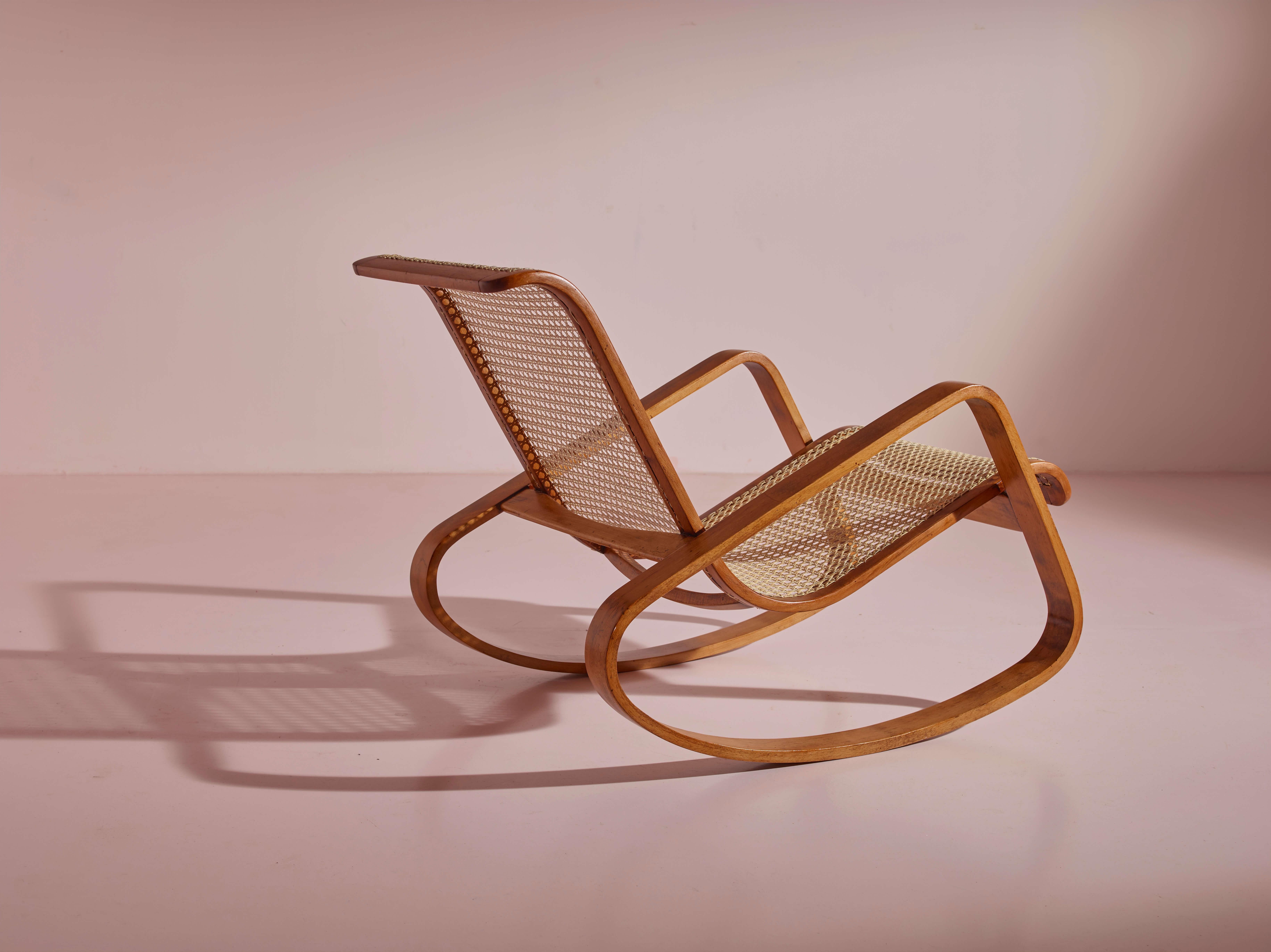 An extraordinary and very rare rocking chair originating from the 1930s, meticulously crafted and designed by Ditta Porino of Torino, Italy.

The design of this piece evokes awe through its profound simplicity. A solitary caned seat delicately rests