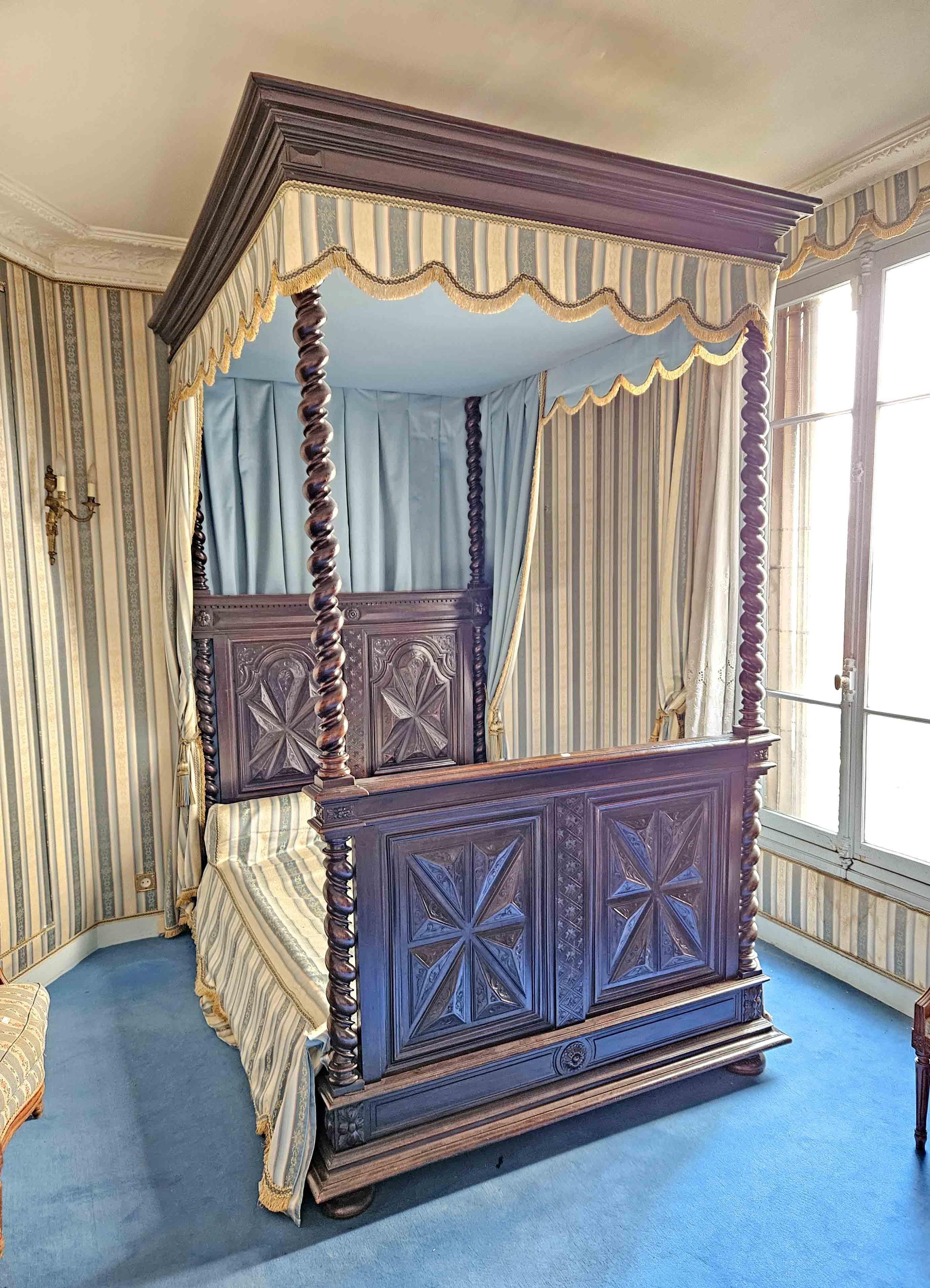 Canopy bed, in molded and carved solid wood, headboard and footboard with diamond-point decoration, architectural moldings and Solomonic columns. The canopy with hangings and trimmings also rests on Solomonic columns.

 XIXth century, in the style
