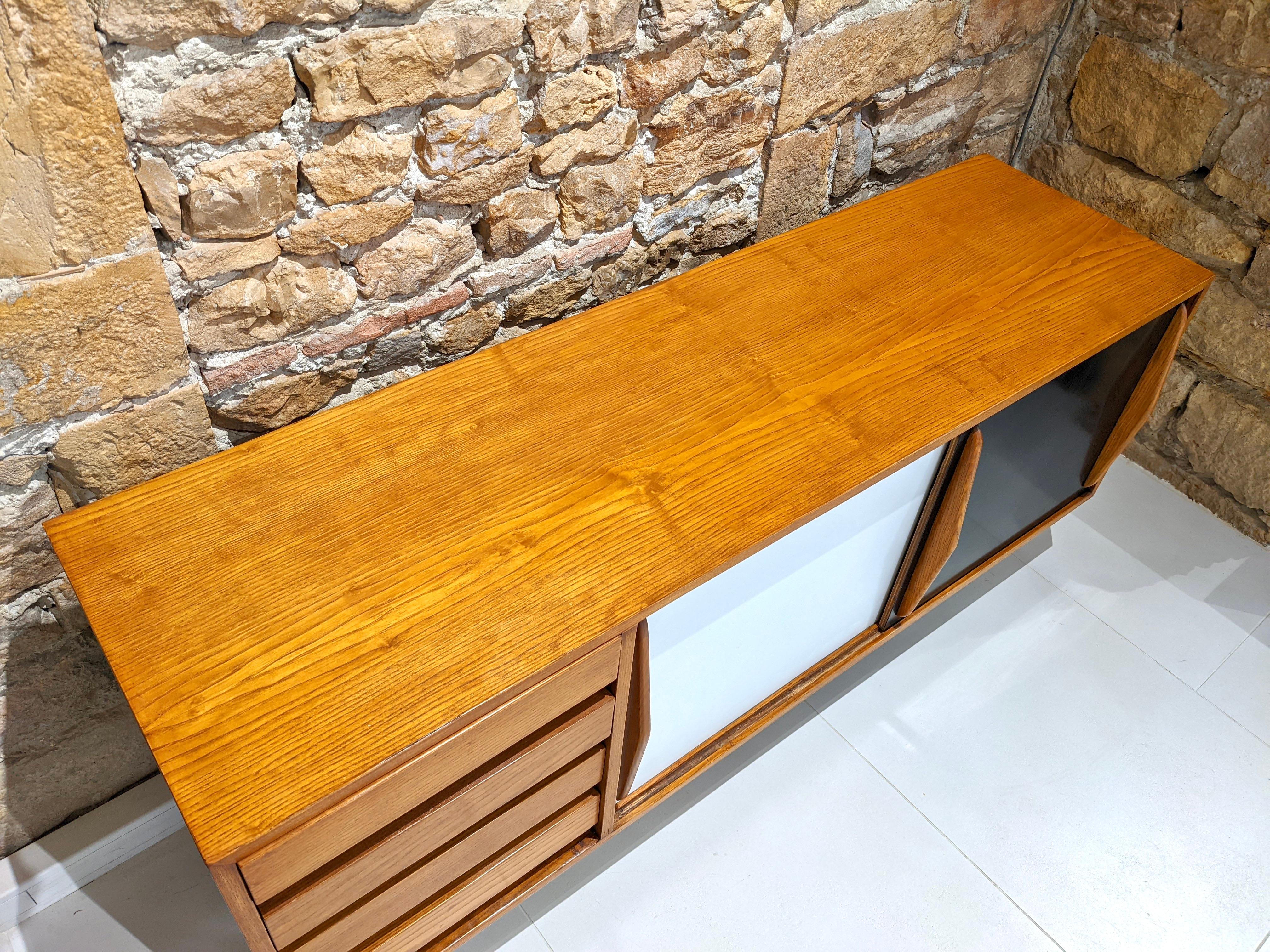 Cansado sideboard in ash with drawers by Charlotte Perriand.
Circa 1954
Very good condition.
 Miferma in Mauritania 
The base is in black lacquered metal (also with a nice patina).
The wood has been varnished and the bottom of the drawers is