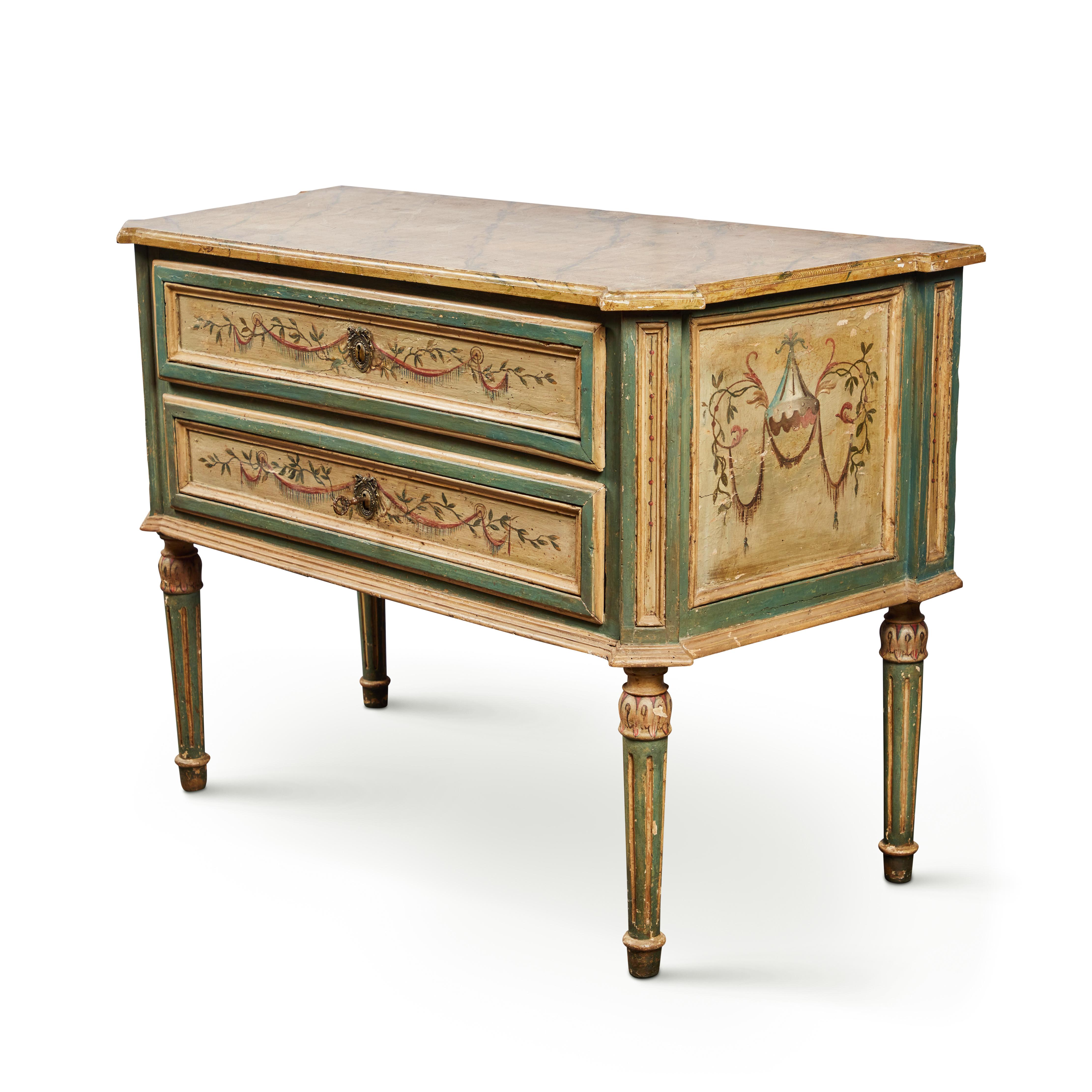 An absolutely charming, hand-carved and painted, two drawer commode surmounted by a faux marble top. The paneled body in in painted vines and swags of ribbon centered on the raised, gilt bronze escutcheons. The whole on fluted, tapered legs.