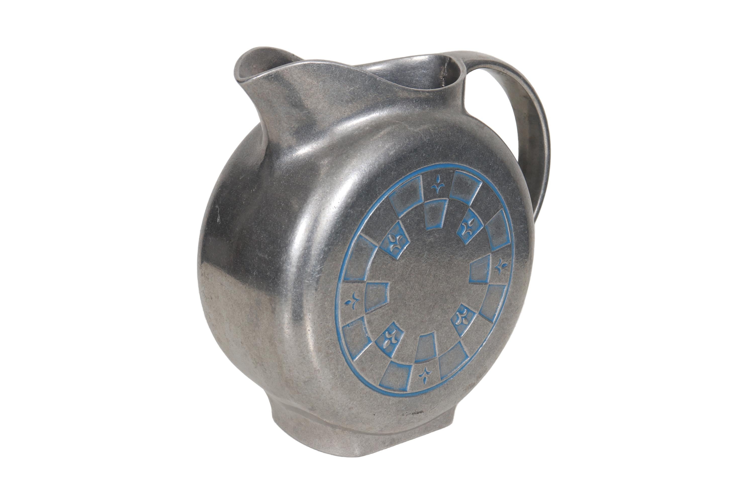 A cast armetale water pitcher made by Wilton. Shaped like a canteen; round with flat sides. Decorated with an embossed checkered pattern with fleur de lis details in a matte pewter color, accented in blue. Marked underneath 