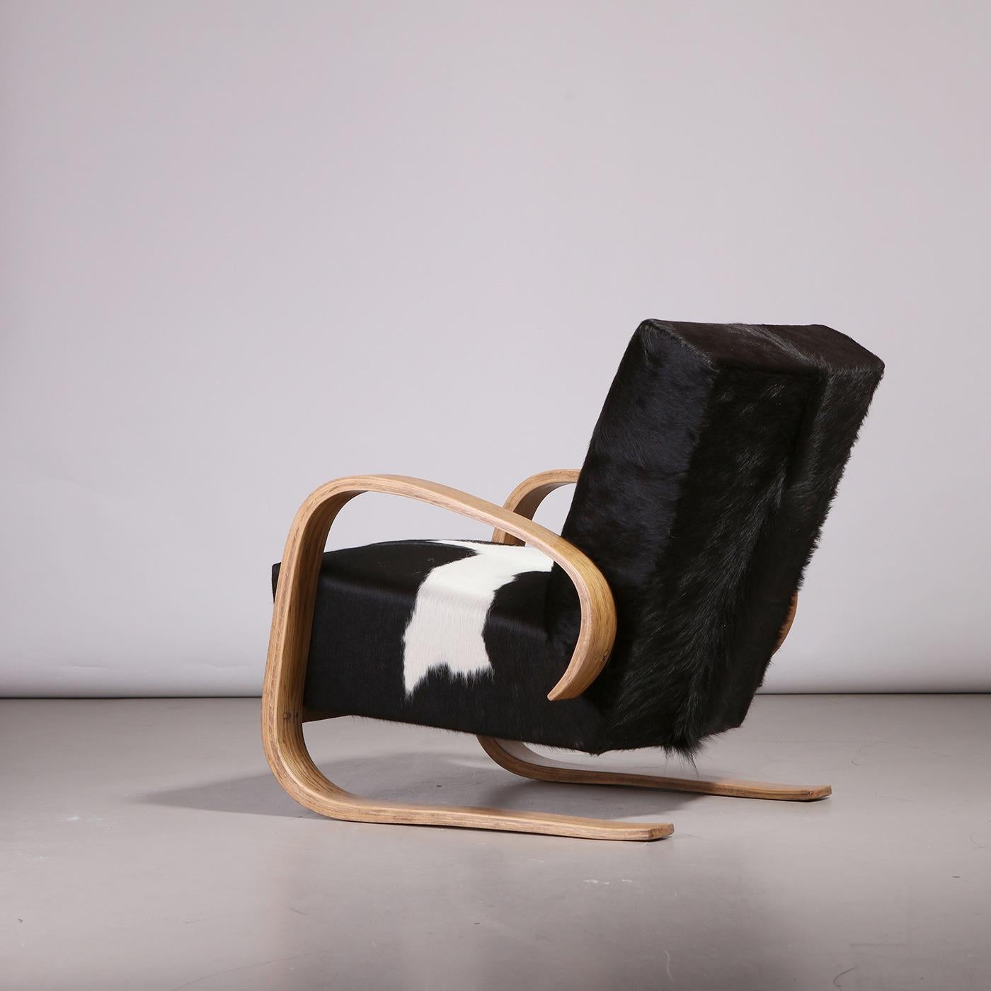 Sedia lounge a sbalzo, creata da un ebanista europeo negli anni Cinquanta. Presenta braccioli in legno ed è stata recentemente rivestita in pelle di mucca. La struttura della sedia presenta dei braccioli a forma di C, che ricordano l'aspetto della