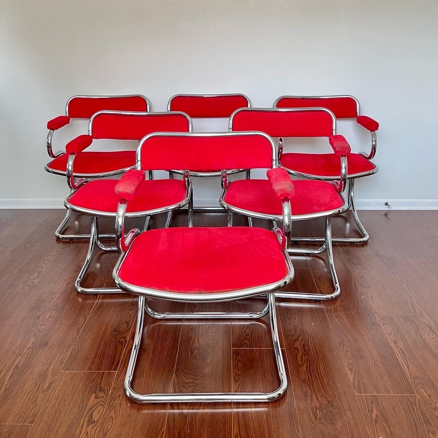 This set of six chairs is nothing short of stunning! These chrome and red velvet like upholstered chairs are made by Bassett Mirror Co. Inc. in the style of Italian designer Gastone Rinaldi. Their curvaceous reverse cantilevered chrome design is not