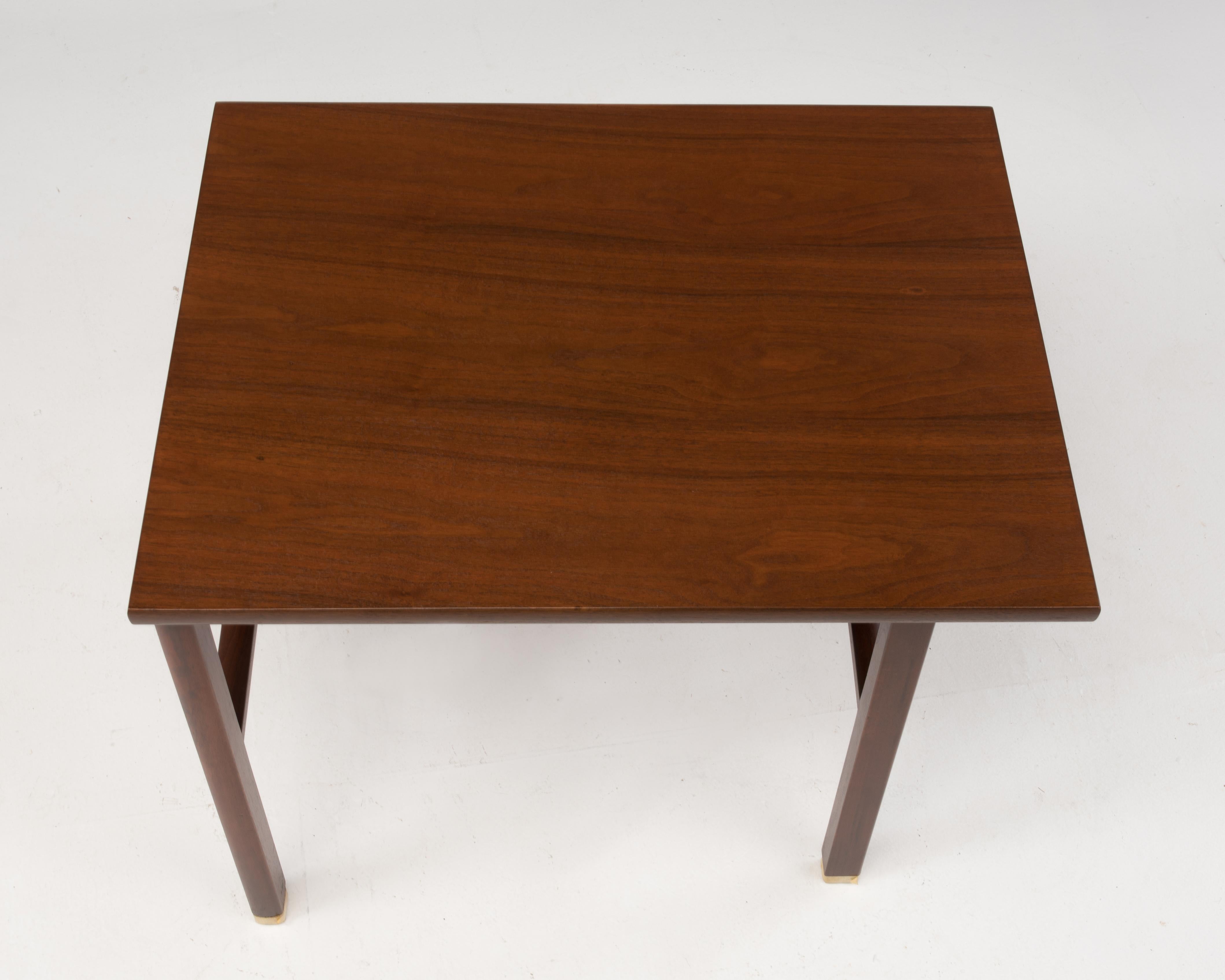 Cantilevered teak end table by Edward Wormley for Dunbar, circa 1960s. Features cantilevered top and brass feet. Retains the original Dunbar brass tags.
