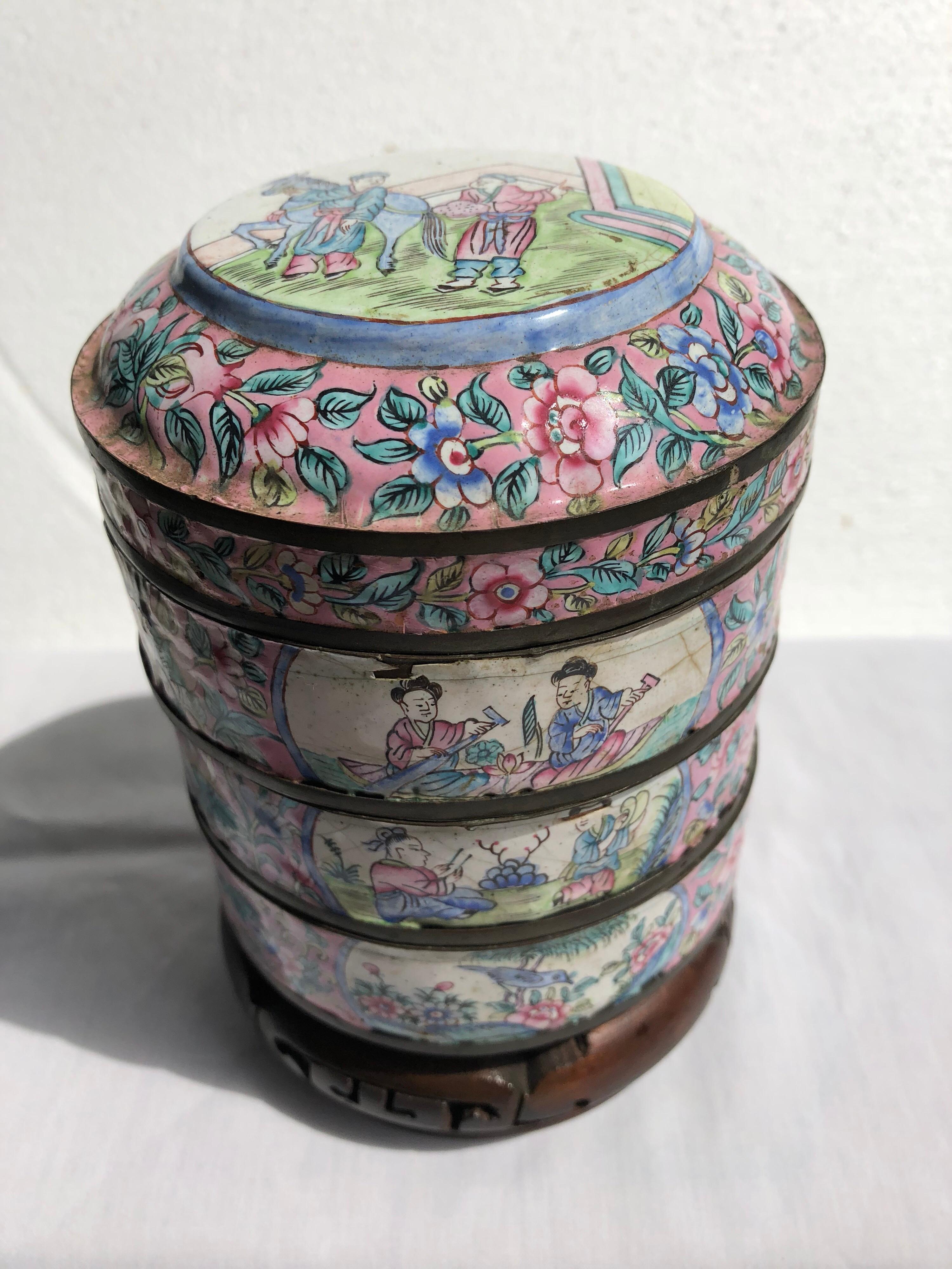 Canton enamel three part round jar on carved stand. Top piece shows two gentlemen with a horse.
One side shows men in a row boat, one playing musical instruments and the third a bird in a
garden. The other side has a fishing scene, tea drinking