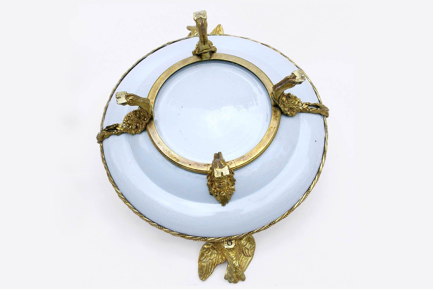Canton porcelain plate mounted in chiseled and gilt bronze.
Central decor of an Asian scene representing two men and a woman around a table and a third man hidden behind a door. They are on a house deck, overlooking a garden. White marli framed by
