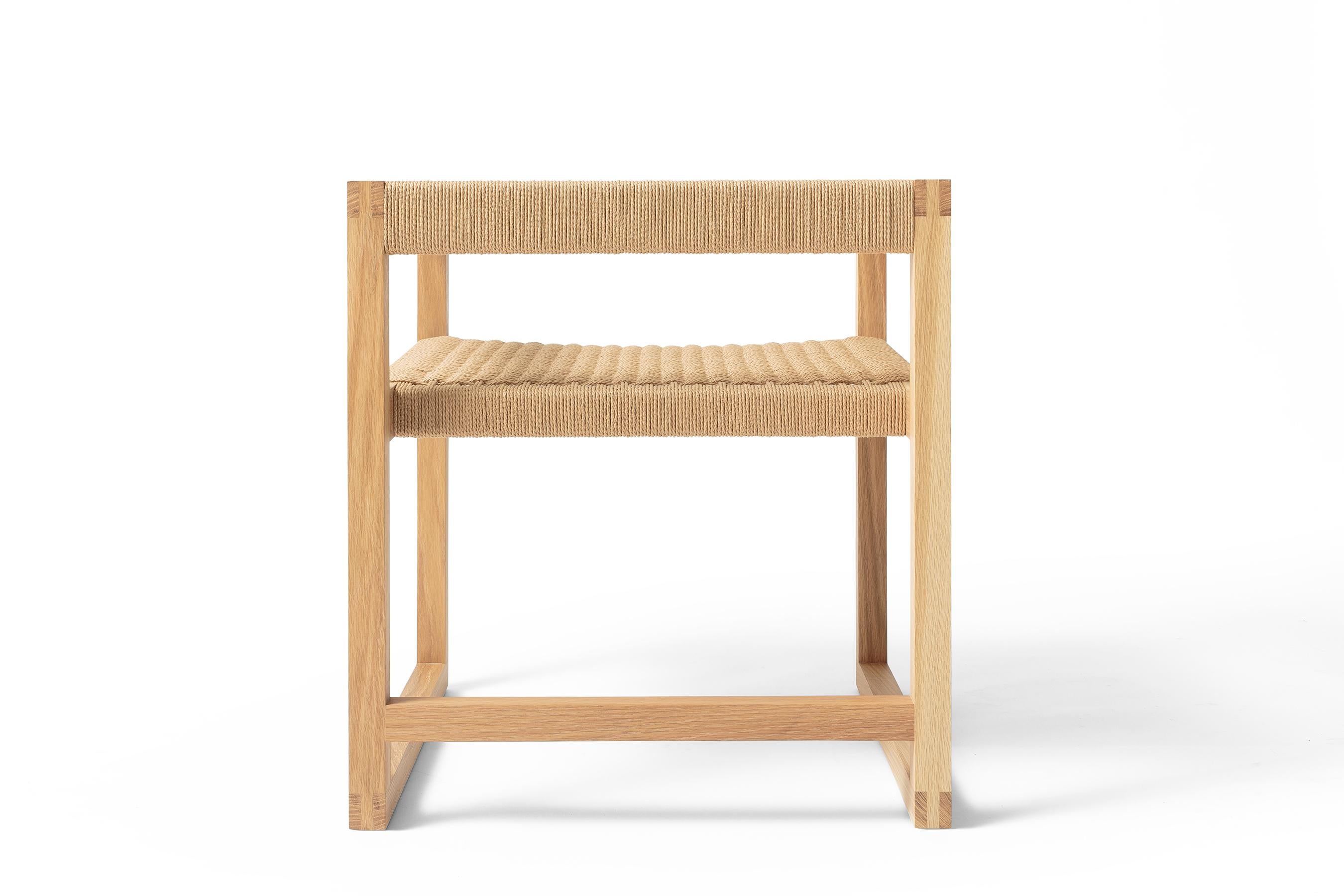 Avec sa menuiserie apparente et un mélange de lignes dures et douces, la Canva Chair explore l'amour des matériaux et de l'artisanat, associé à un accueil chaleureux. Construite avec une armature apparente à joints de brides et un siège tissé à la