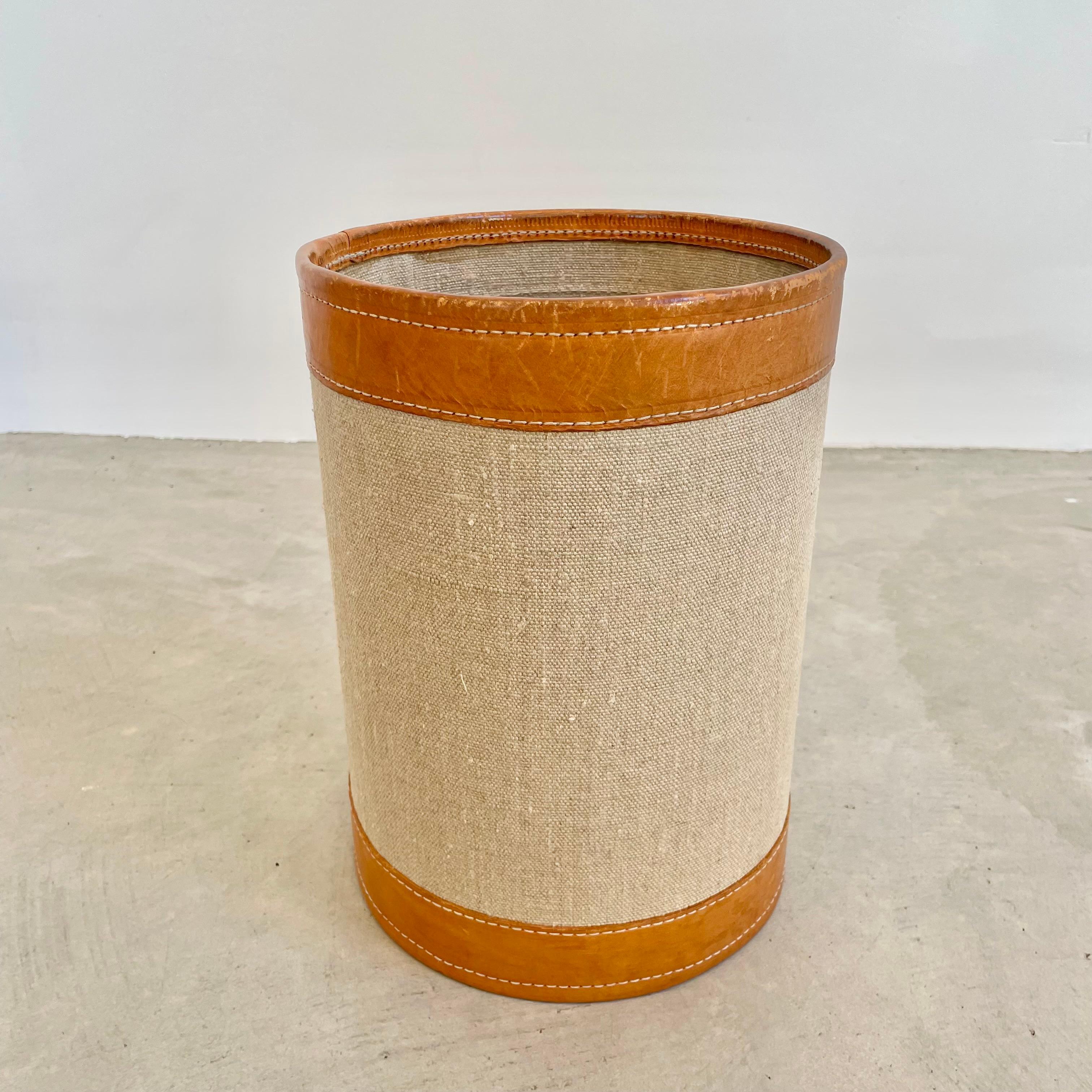 Beautiful taupe canvas tan leather waste bin. Sturdy cylindrical body wrapped in a hardy burlap canvas with great leather accents on the brim and base attached with an elegant contrast stitch. Great color and good vintage condition. High quality