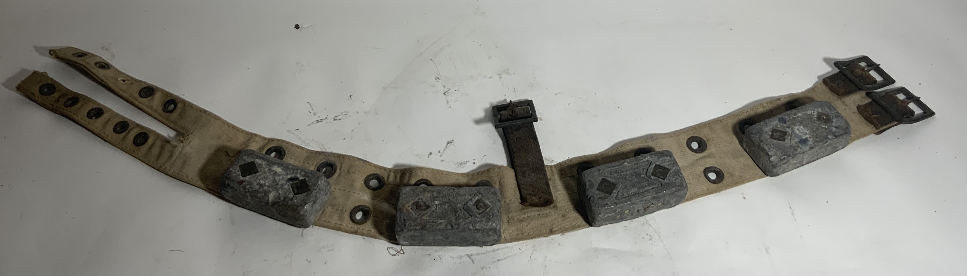 Ceinture de plongée avec plombs. Ceinture de plongée du milieu du vingtième siècle avec quatre plombs attachés et de lourdes sangles. La ceinture est une toile lourde. Les poids en plomb sont fixés à l'aide d'une boucle en laiton. Superbe relique de