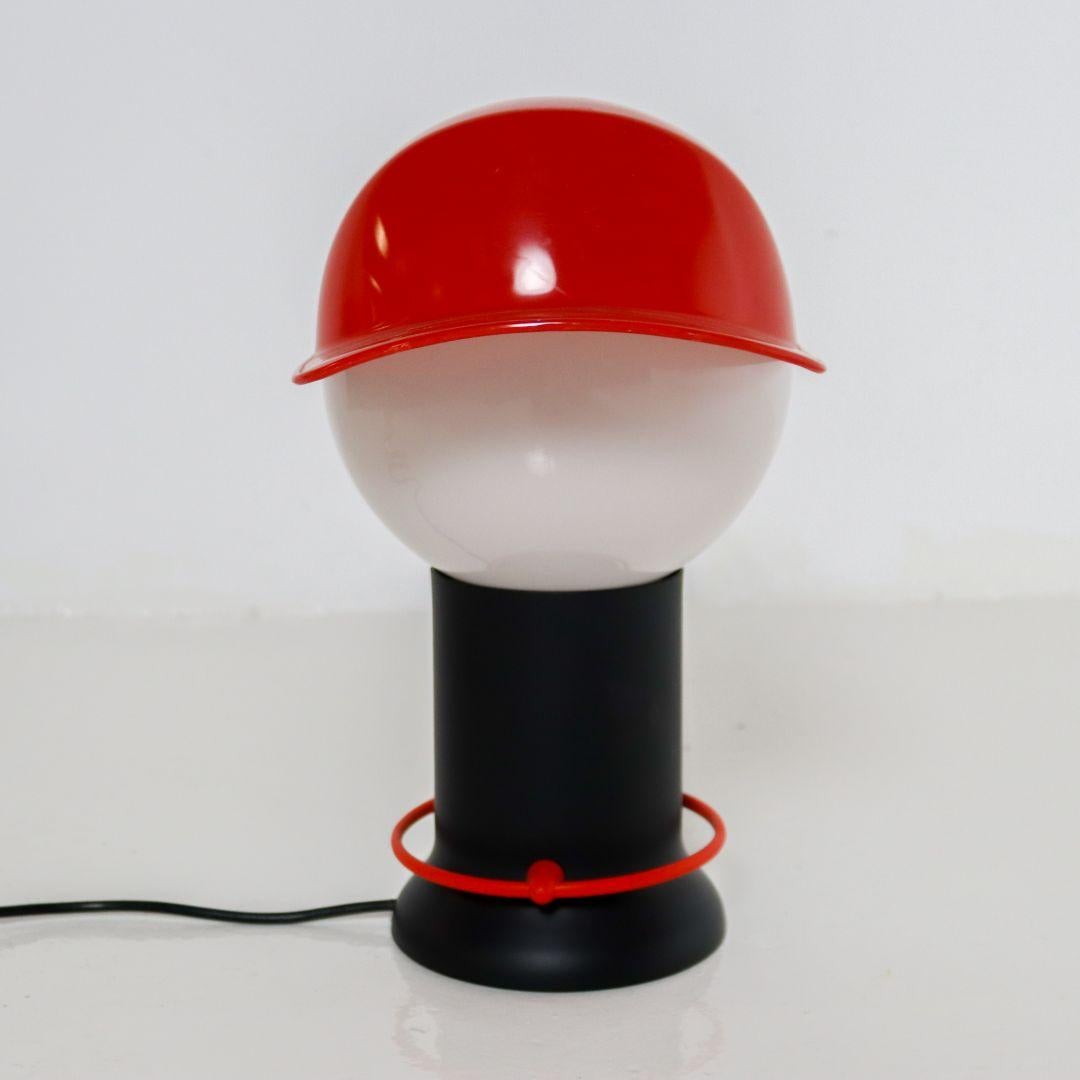 Alegre lámpara de sobremesa de plástico de los años 80, obra del diseñador italiano Giorgetto Giugiaro para Bilumen. El interruptor de encendido/apagado es un anillo de plástico rojo alrededor de la base de la lámpara, que se enciende y apaga