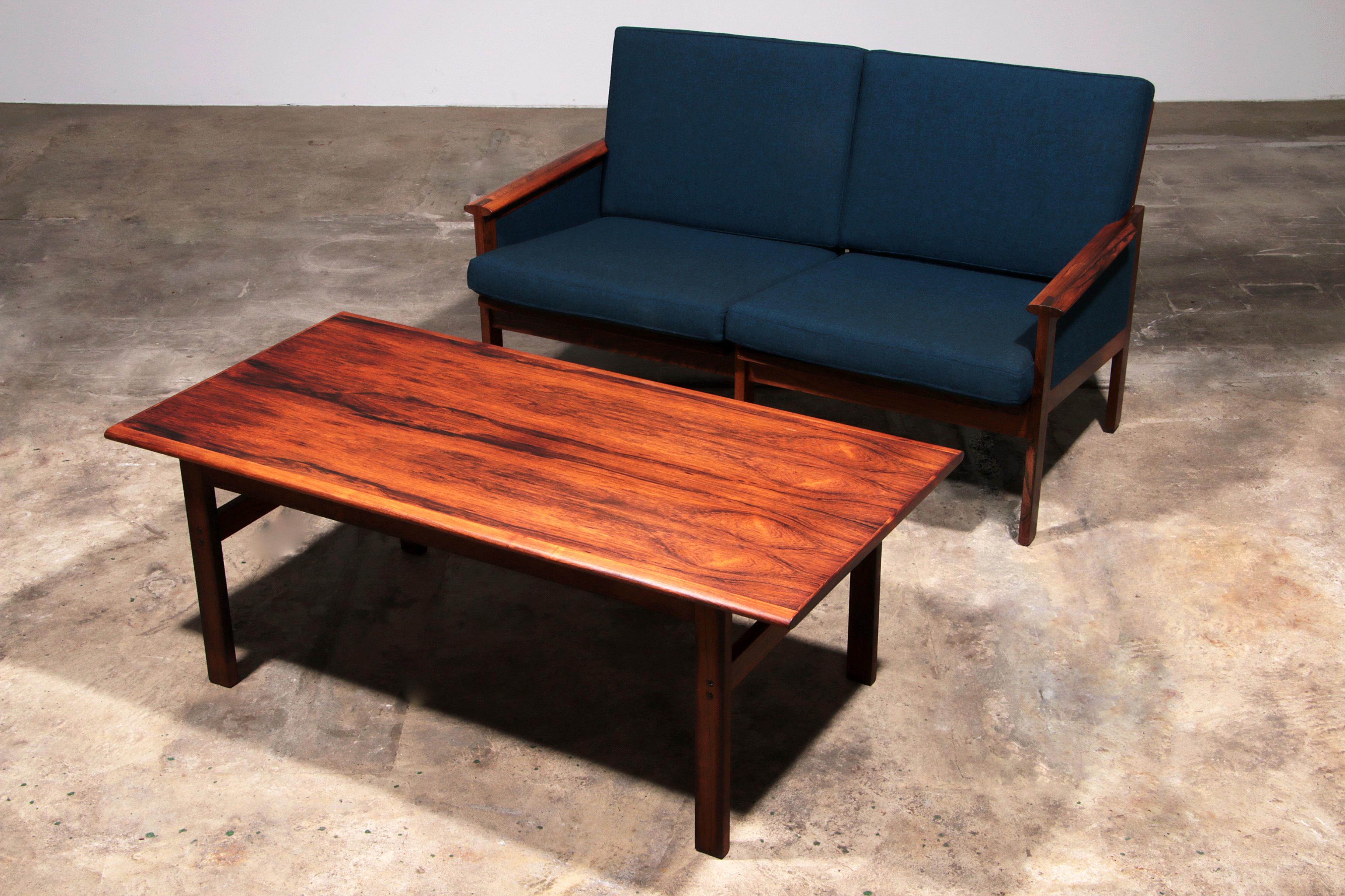 Step back into the golden age of Danish design with this classic rectangular coffee table from the Capella series, crafted by renowned designer Illum Wikkelsø in the 1960s for Niels Eilersen. Also the bench,with new cushes in bleu fabric. Made from