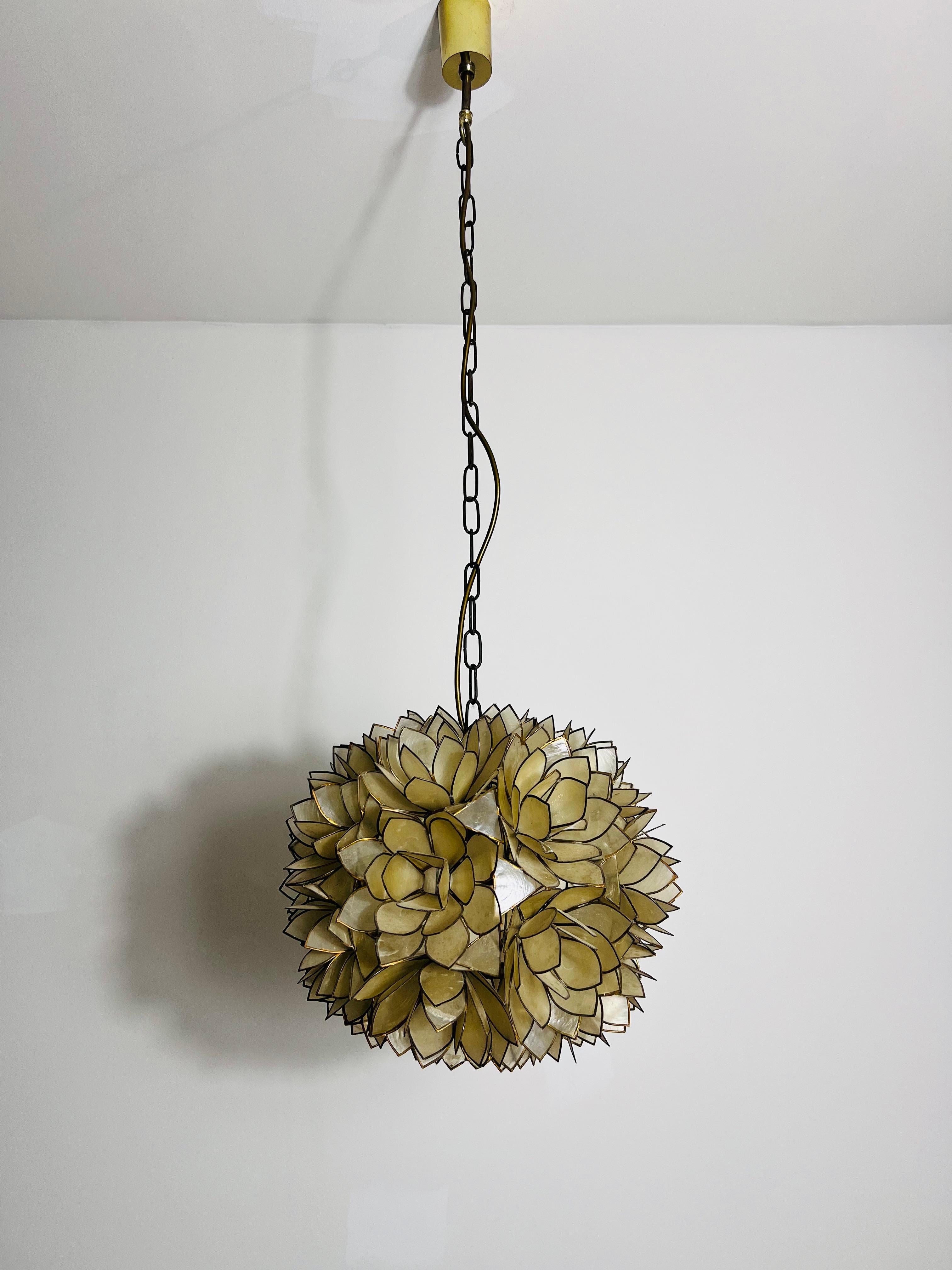 Dieser exquisite Kronleuchter fängt die zarte Schönheit einer Lotusblume ein. Er ist ganz aus schimmernden Capiz-Muscheln gefertigt, die das Licht anmutig reflektieren und ein sanftes, stimmungsvolles Licht erzeugen. Er wurde in den 1970er Jahren in