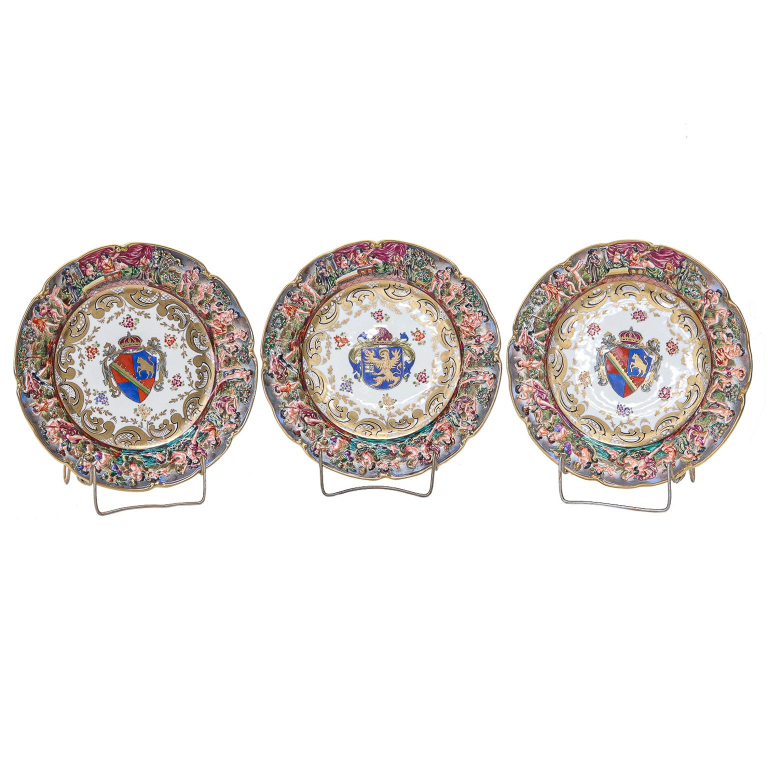An exquisite set of 12 Capo di Monte Armorial porcelain cabinet plates from the late 19th century.
Each is painted with a unique familial crest in the center with a gilt border, scrolled, and dotted scrolls. The rims are raised with bacchanalian