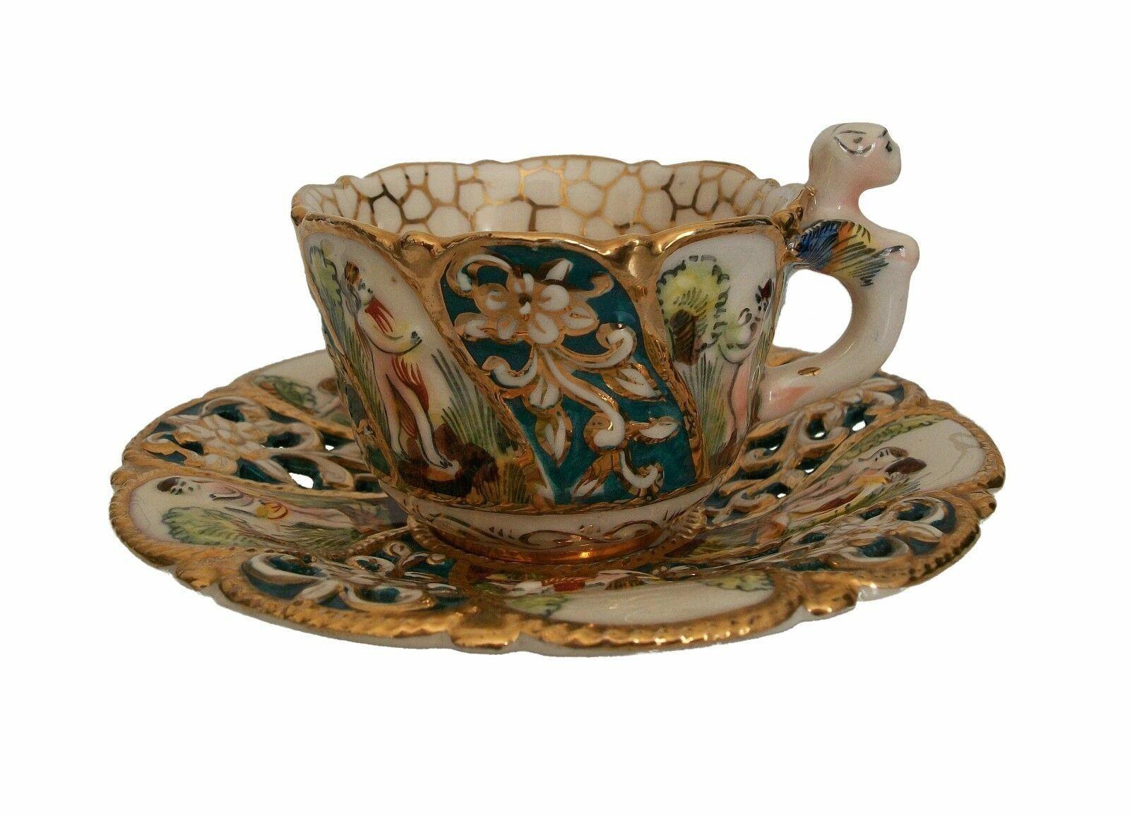 CAPODIMONTE - Fine quality Italian provincial hand painted gilt ceramic cabinet cup and saucer - featuring alternating swirling bands of figures in relief and floral decoration with pierced decoration to the saucer - extensive gilded outlines and