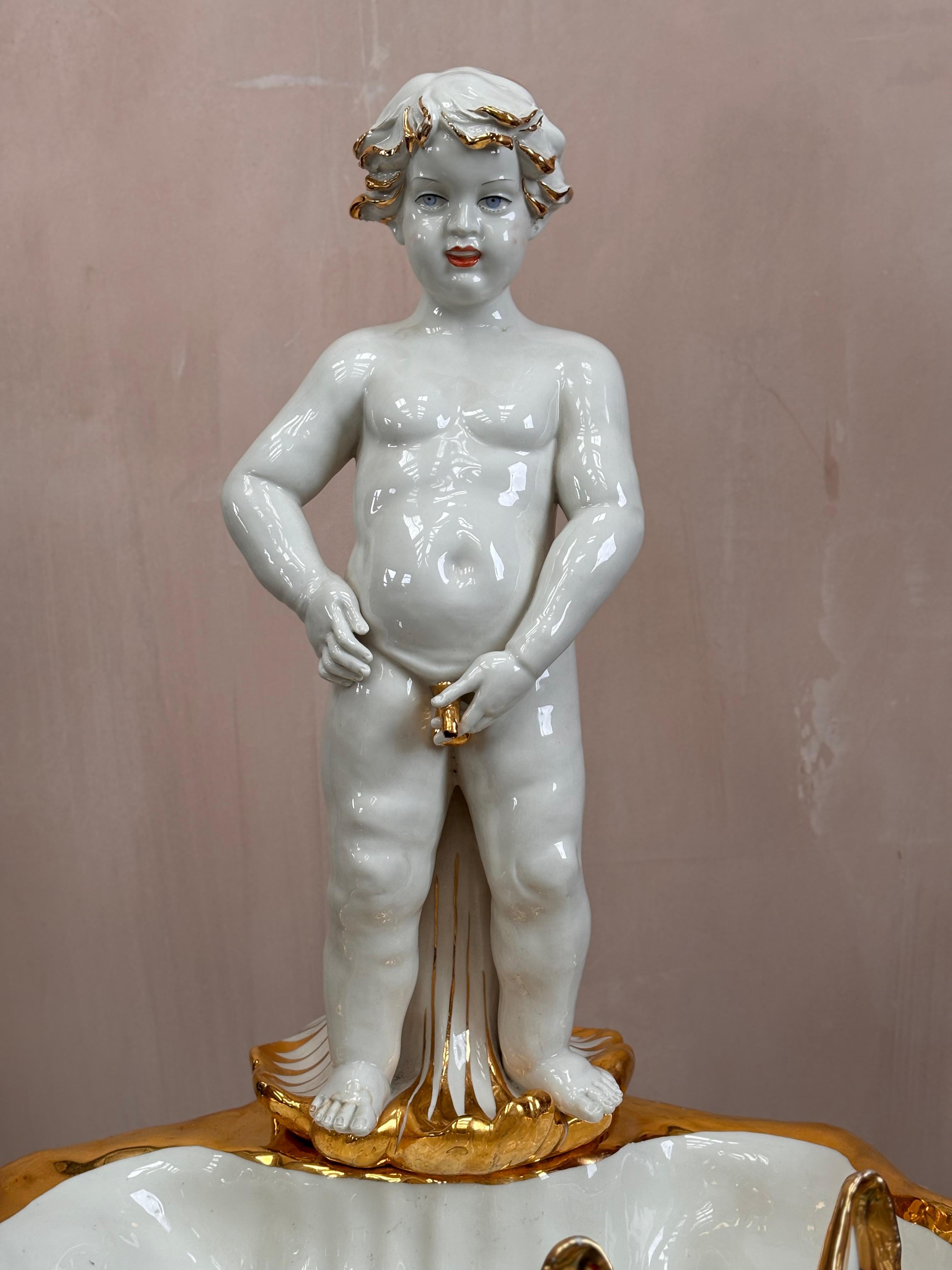 19th century Capodimonte porcelain indoor water fountain. 

A beautiful cherub stands on a large clam, with gold plated finishing. Sign and stamped with the Capodimonte stamp. 

Cherub lifts off the clam shell to revel a tube that is inserted into a