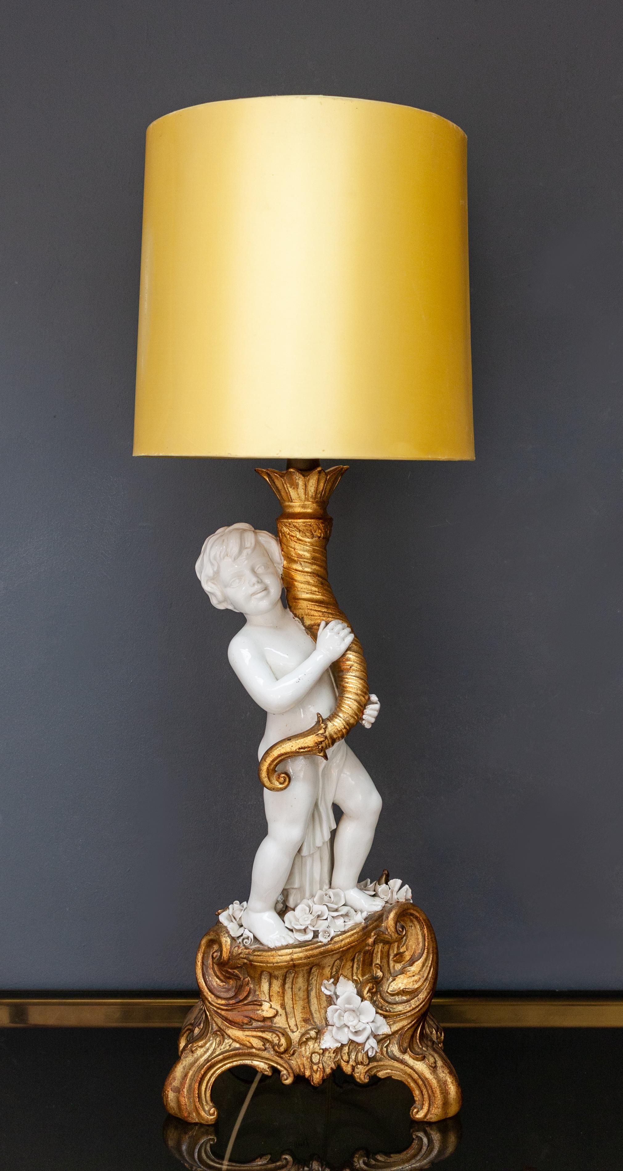 Lámpara de porcelana italiana Capodimonte con querubín y cornucopia. Con flores de porcelana blanca. Sobre una base de imitación de madera, la base también es de porcelana. Soporte de lámpara de muy buena calidad. Buen estado, años 50. Hollywood