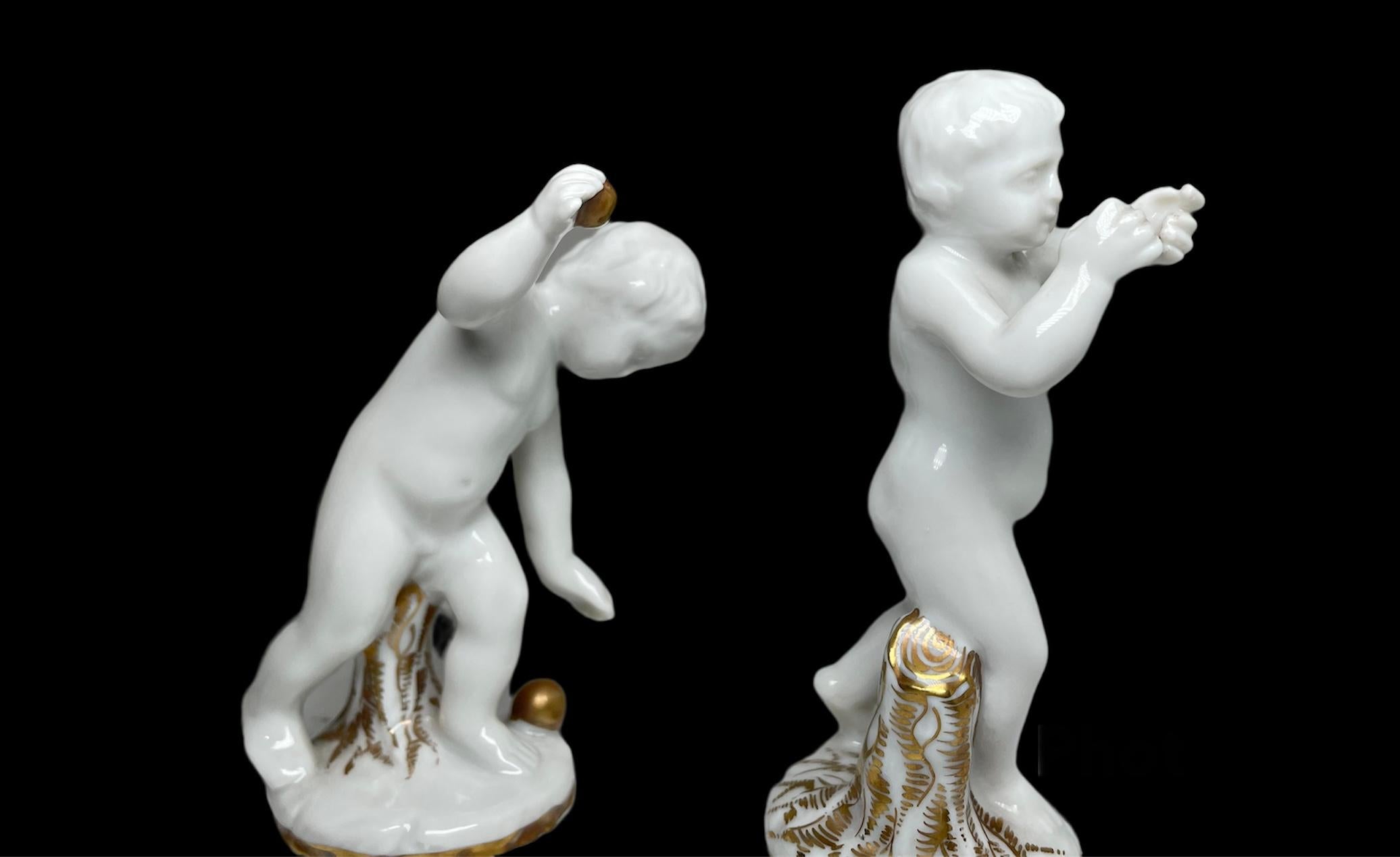 This is a pair of Capodimonte glazed white Parian porcelain nude cherubs who are playing with some gilt round small balls. Both of them are standing near an old cut gilt tree trunk. One of them is trying to throw the ball and the other one is