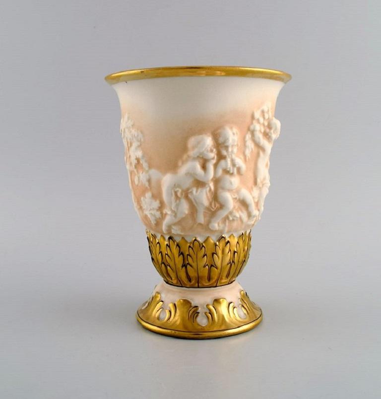 Capodimonte, Italy. Antique porcelain vase with putti in relief and hand-painted gold decoration. 
Early 20th century.
Measures: 18 x 13.5 cm.
In excellent condition.
Signed.