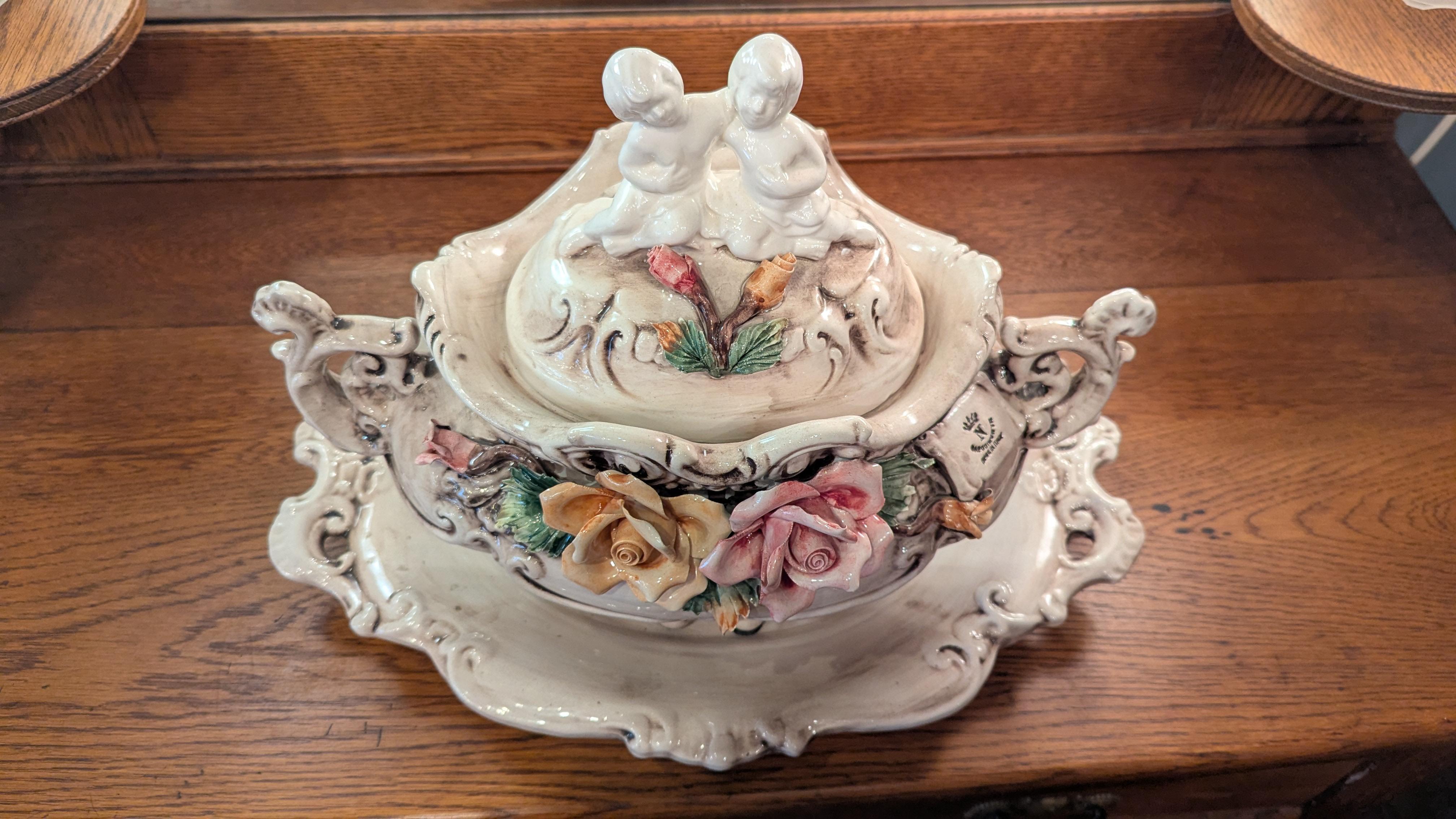 Beautiful vintage Capodimonte toureen, cherub hood and underplate in perfect condition.  The tray is 12.5 x 18.5 x 2, the Toureen is 9 x 15.5 x 12high.  With filigree abound and large roses, the hood features two cherubs on top, signed Capodimonte