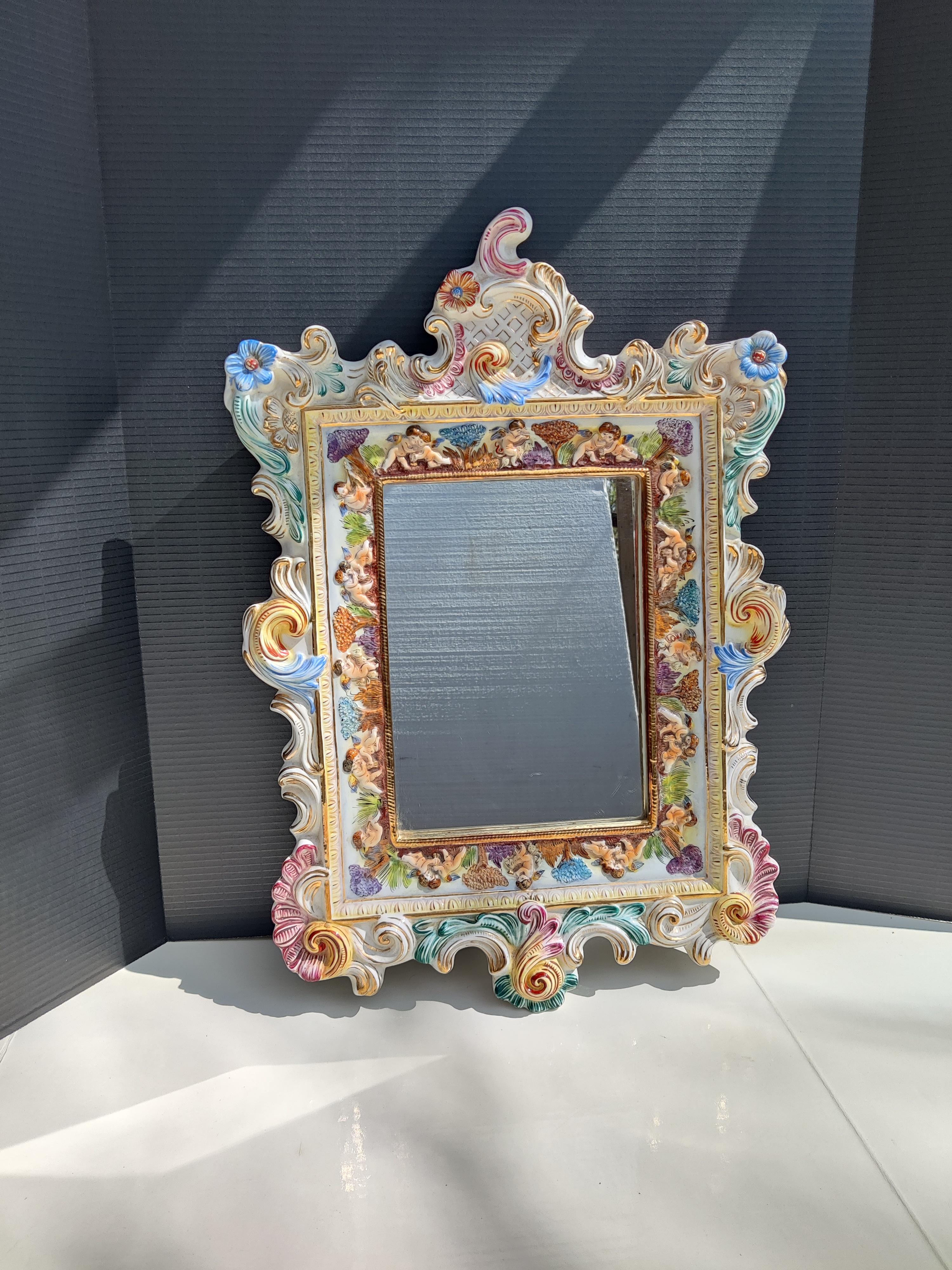 Capodimonte Mirror Italian
Rococo frame decorated with cherubs.
Excellent condition, not chips or damage.
Signed on back R. Capodimonte and R. San Marino. 
Mirror 11.5 x 8.38.