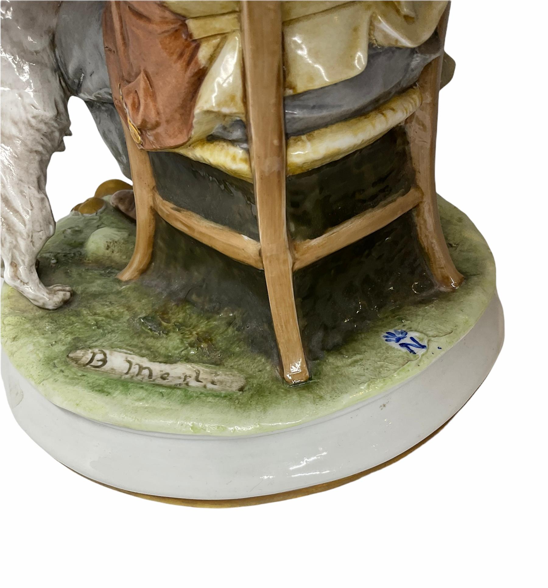 This is a Capodimonte porcelain sculpture of a drunk man with a grey hat and his white terrier dog. He is seated in a chair holding a wine bottle with a grouchy look. He is wearing a brown vest over a pink long leaves shirt, grey pair of pants and