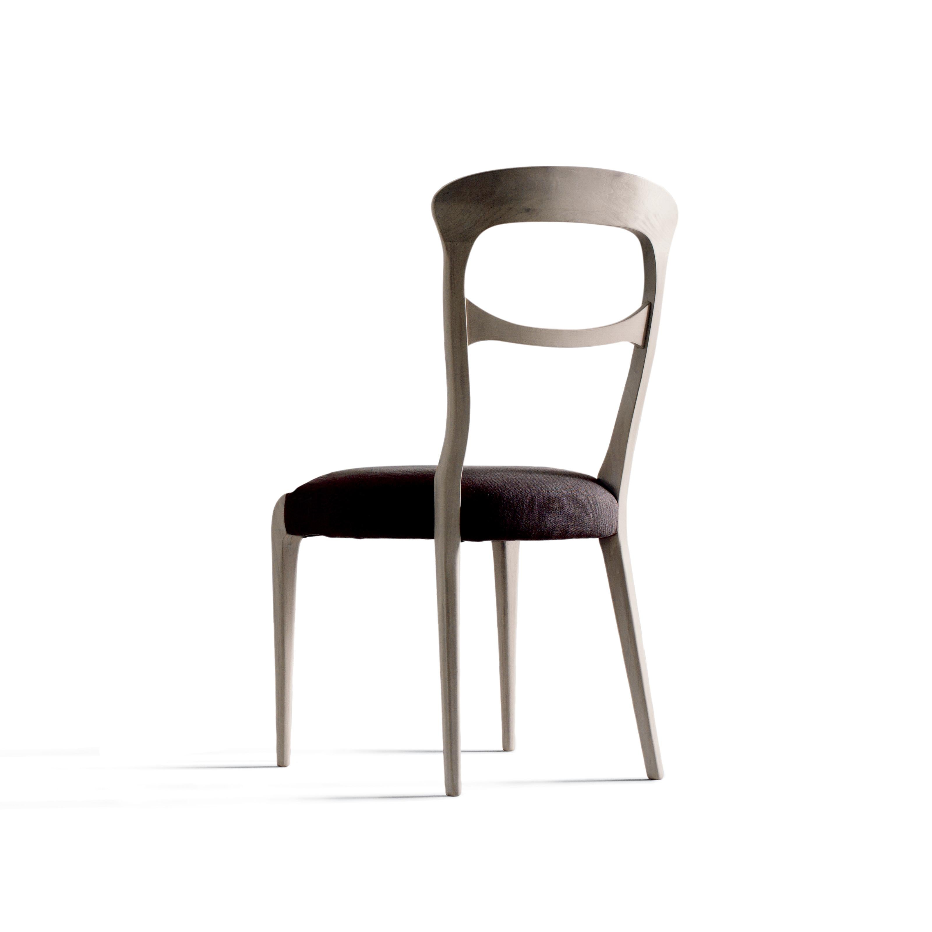 The Capotavola solid wood chair embodies the refined elegance of Italian design. Made in Italy by hand, it features solid canaletto walnut structure with acrylic finish and lining in premium leather or fabric in a range of different colors.