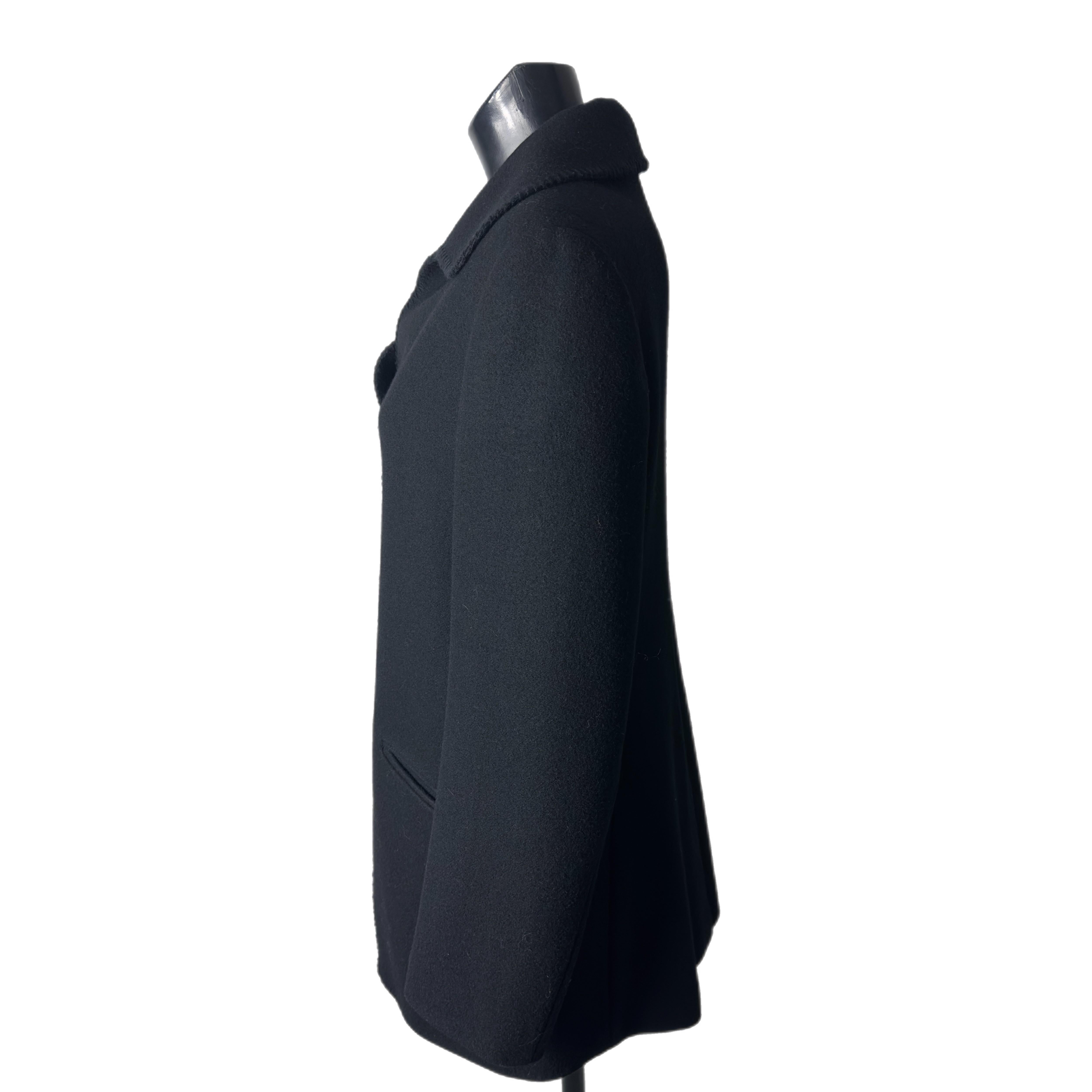 Raro ed iconico cappotto di una delle stiliste più amate Vivienne Westwood 
In lana nera con profili, collo arrotondato e due grandi tasche frontali.
Completano il capo i grandi bottoni logati, che vanno a chiudere la parte alta del capo mentre