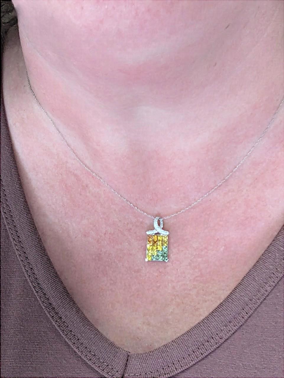 Faites une déclaration audacieuse mais élégante avec notre pendentif Capri en or blanc 14 carats, qui présente un éventail vibrant de saphirs orange, jaunes et verts magnifiquement mis en valeur par des diamants ronds étincelants. Ce pendentif en