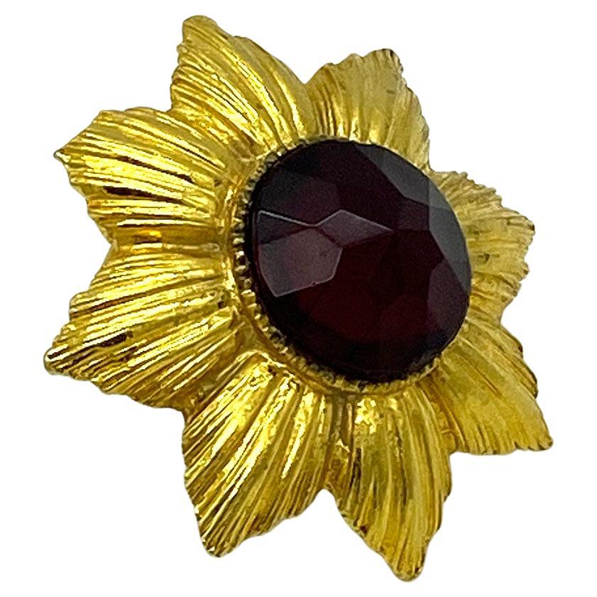 This is a signed Capri jeweled brooch or pendant.  This is an eye catching piece with heavy gold plated metal with a large garnet color faceted jewel set in center. It is reminiscent of a royal medal. Because of it's weigh it will fit a winter heavy